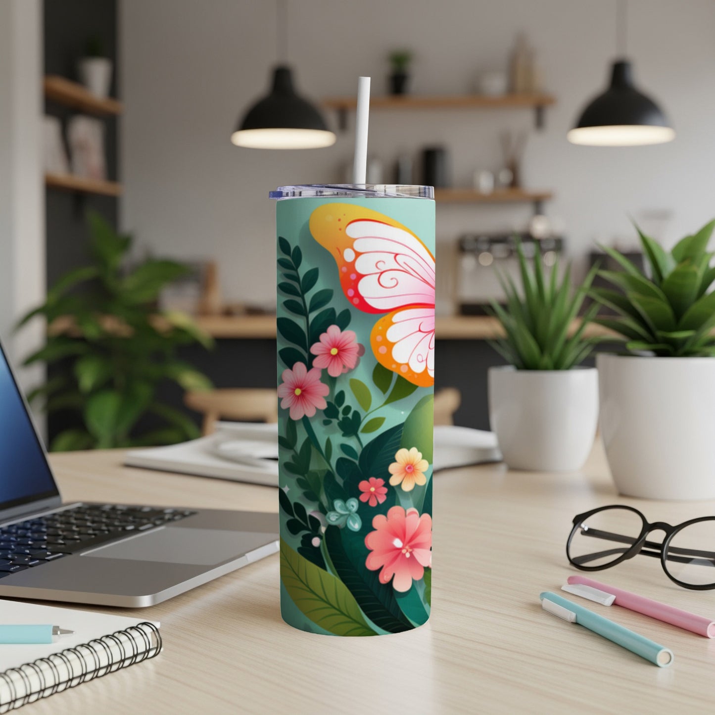 Tall tumbler with butterfly and floral design on desk.