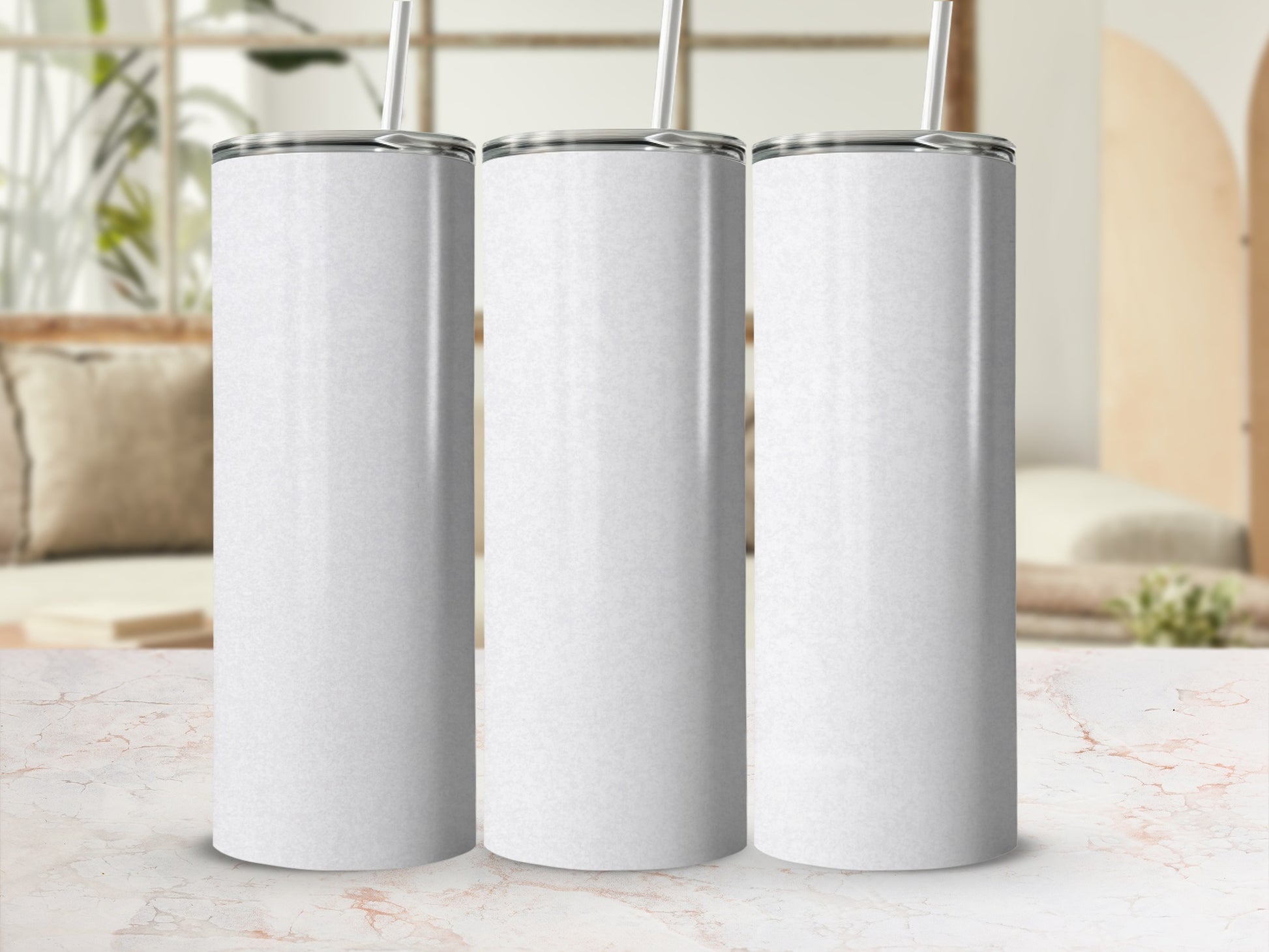 Three white tumblers with straws displayed on a marble surface.