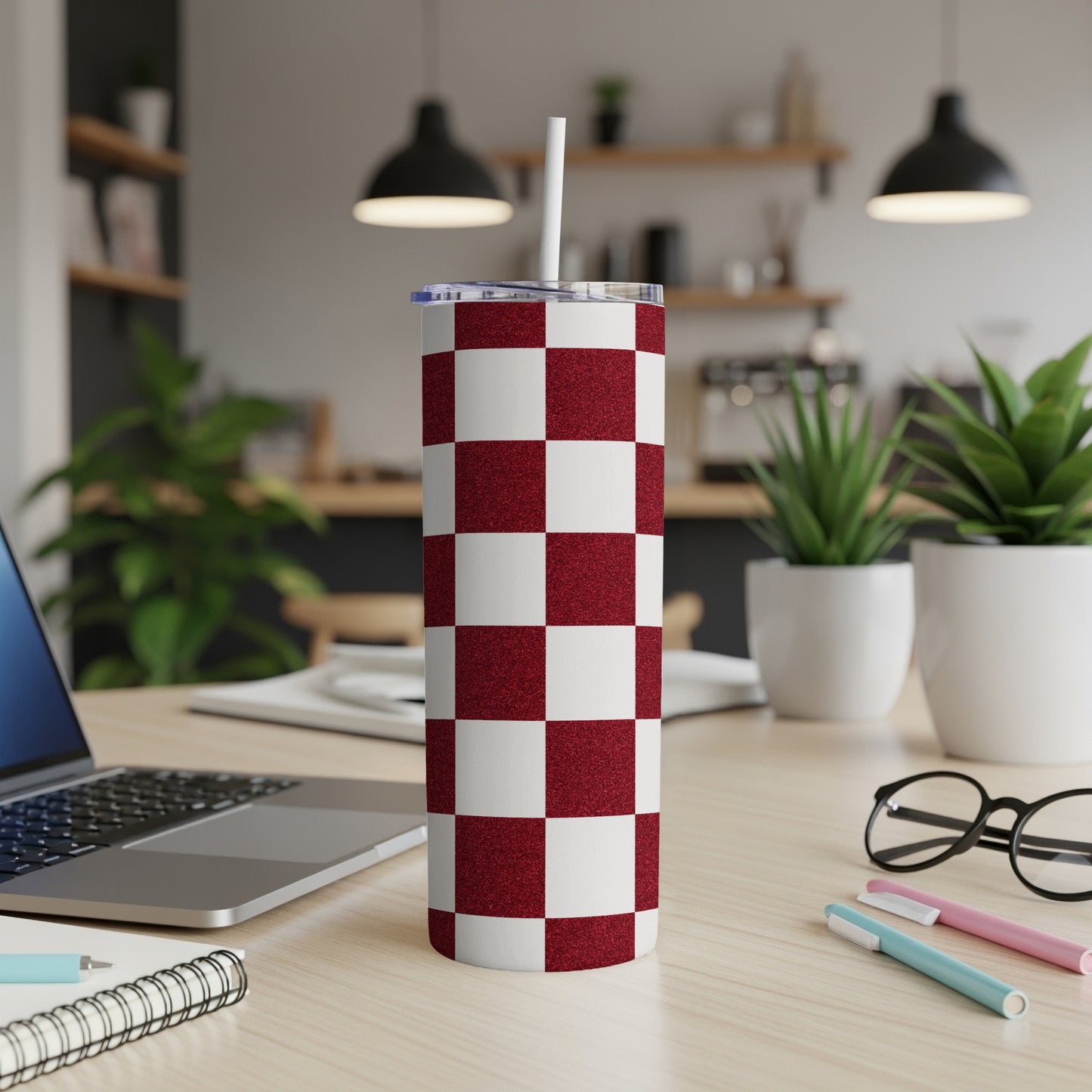 Red and white checkered tumbler with a straw, on a desk.