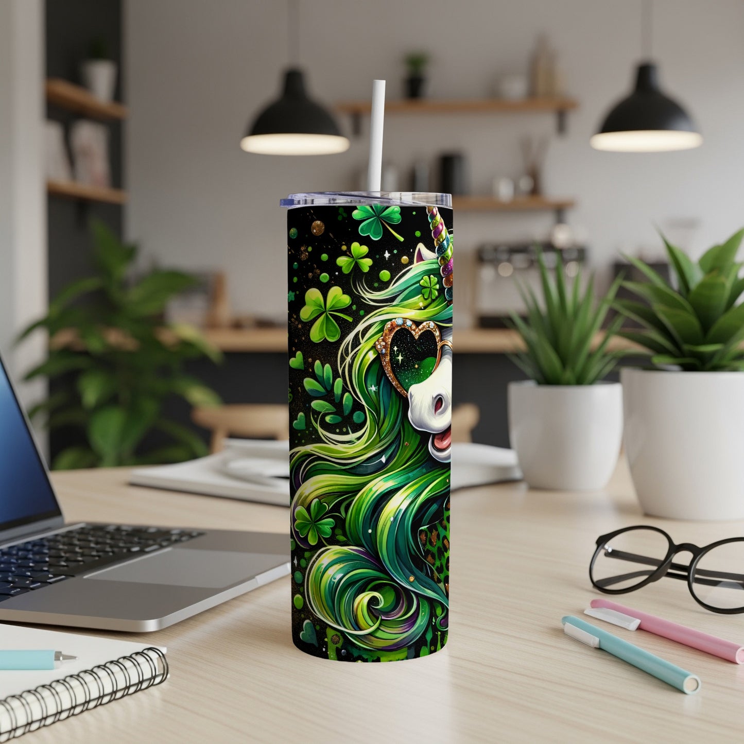 Green unicorn tumbler with shamrocks and hearts, on a desk.