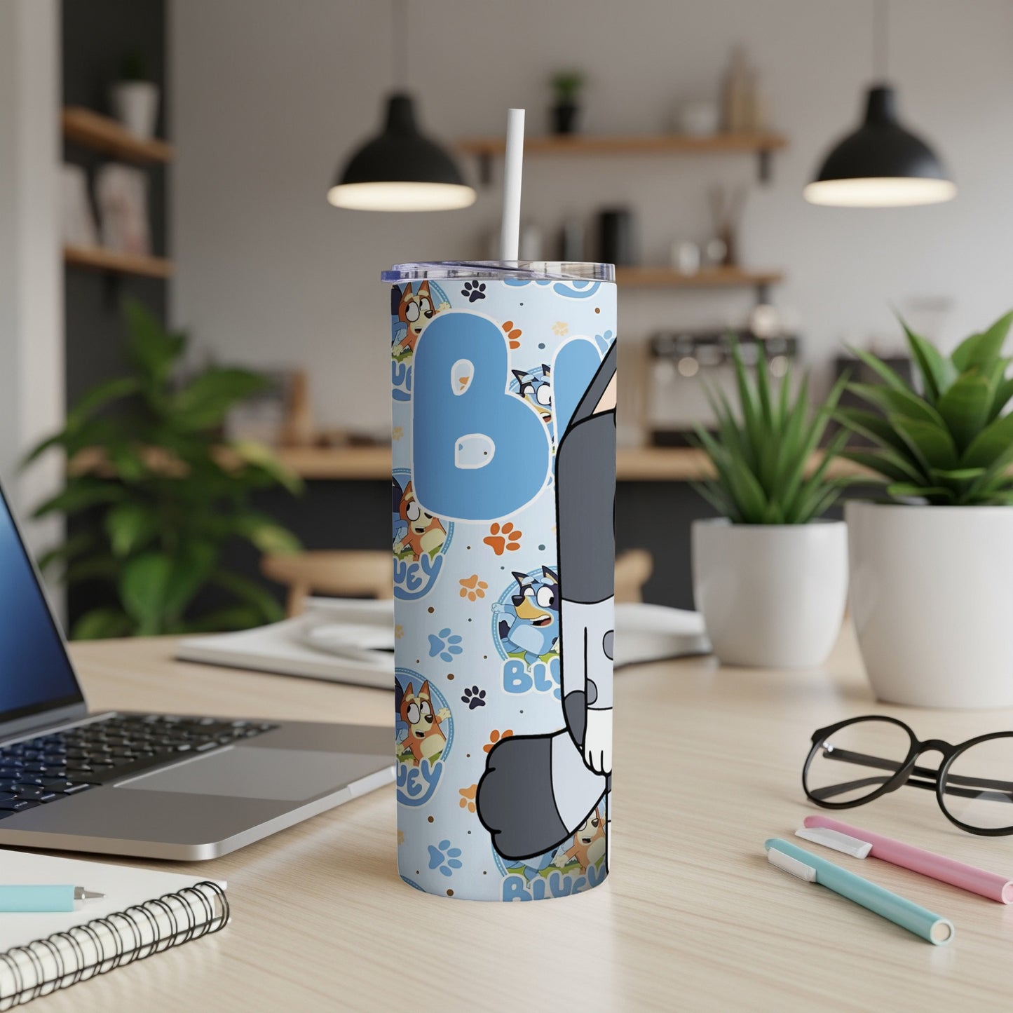 Bluey cartoon characters on a light blue tumbler with straw, on a desk.