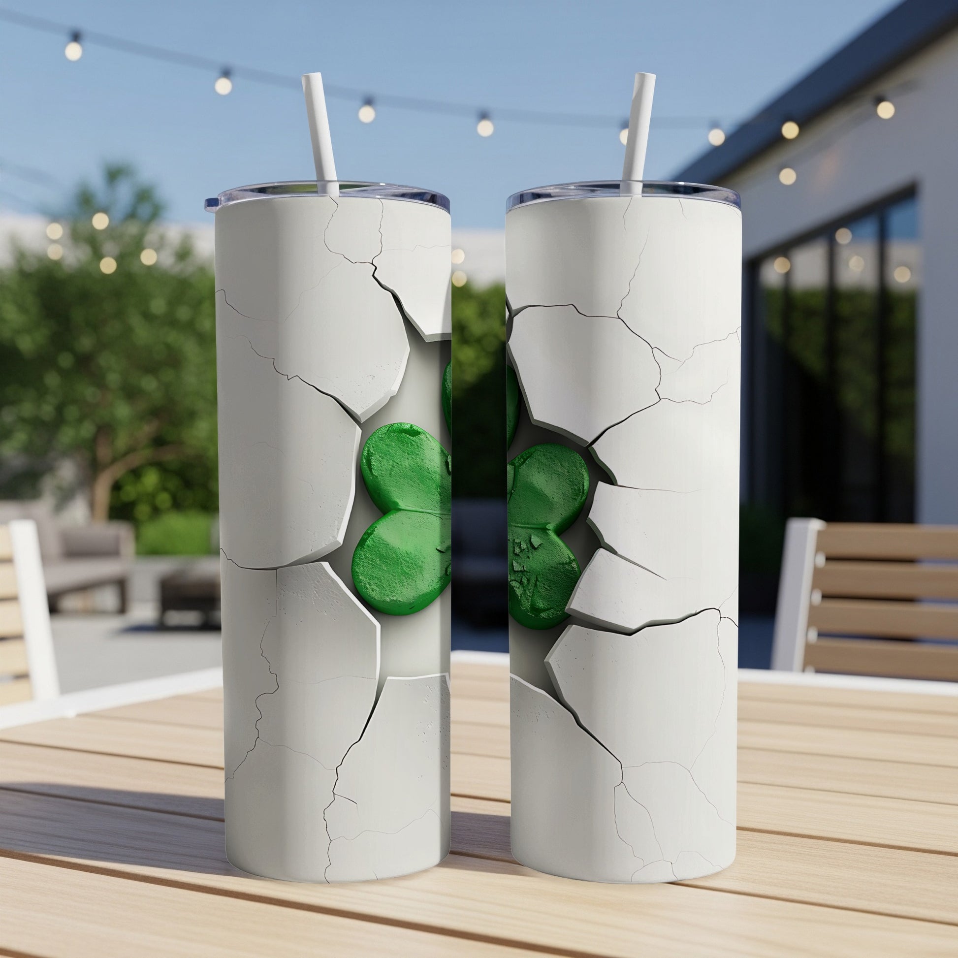Two cracked white tumblers with green shamrocks on a table.