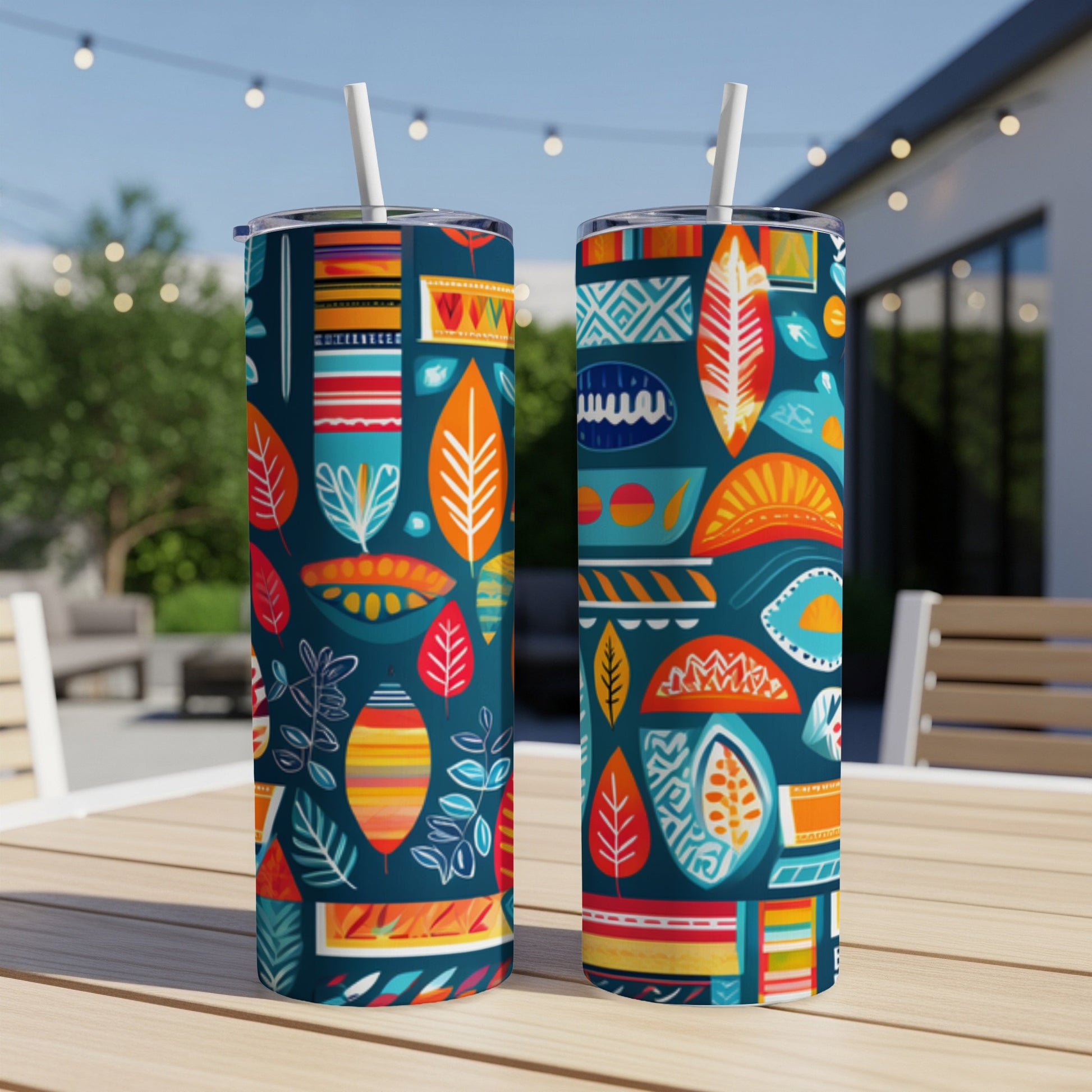 Two tumblers with colorful abstract patterns and leaves on a table.