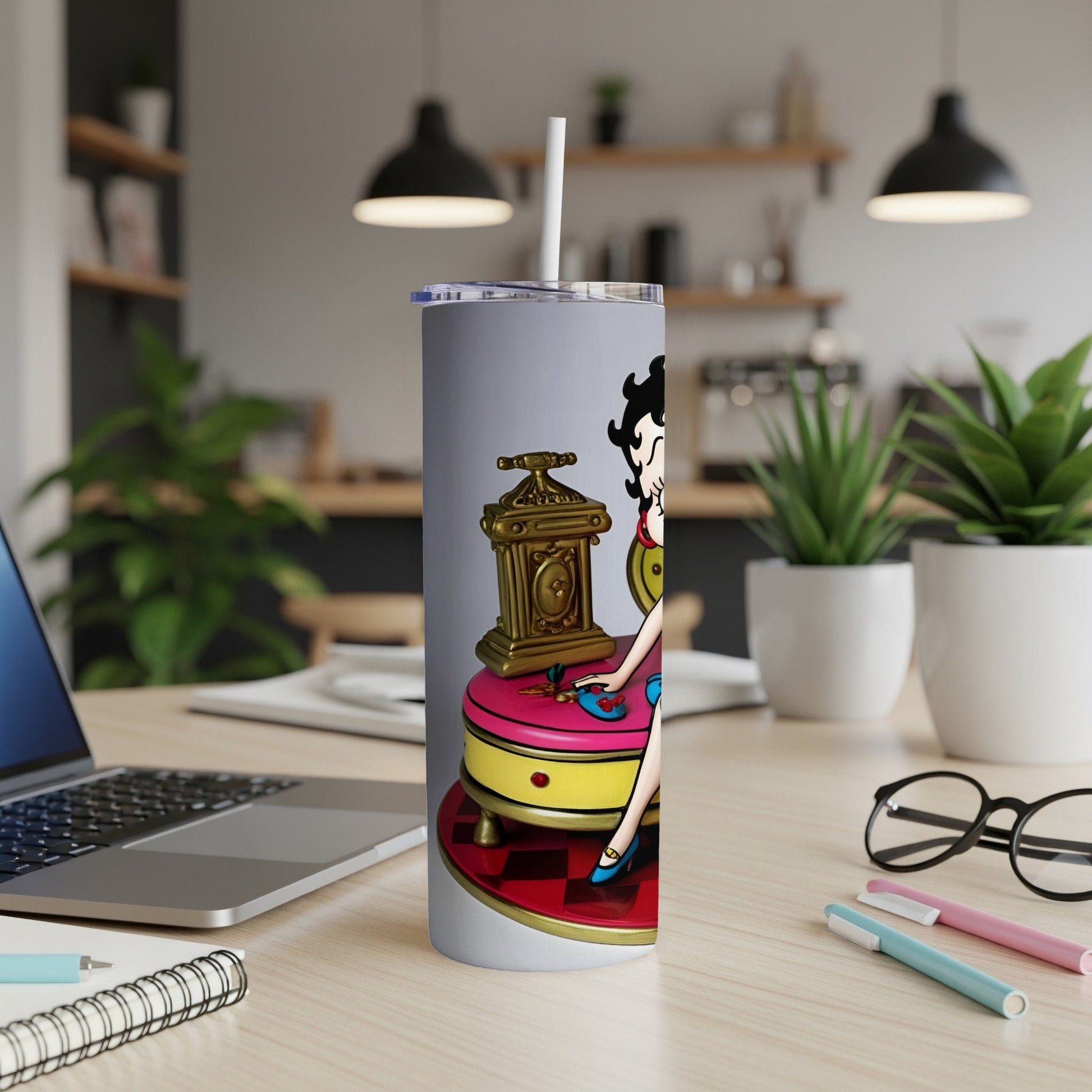Betty Boop figurine on a clock next to a laptop on a desk.