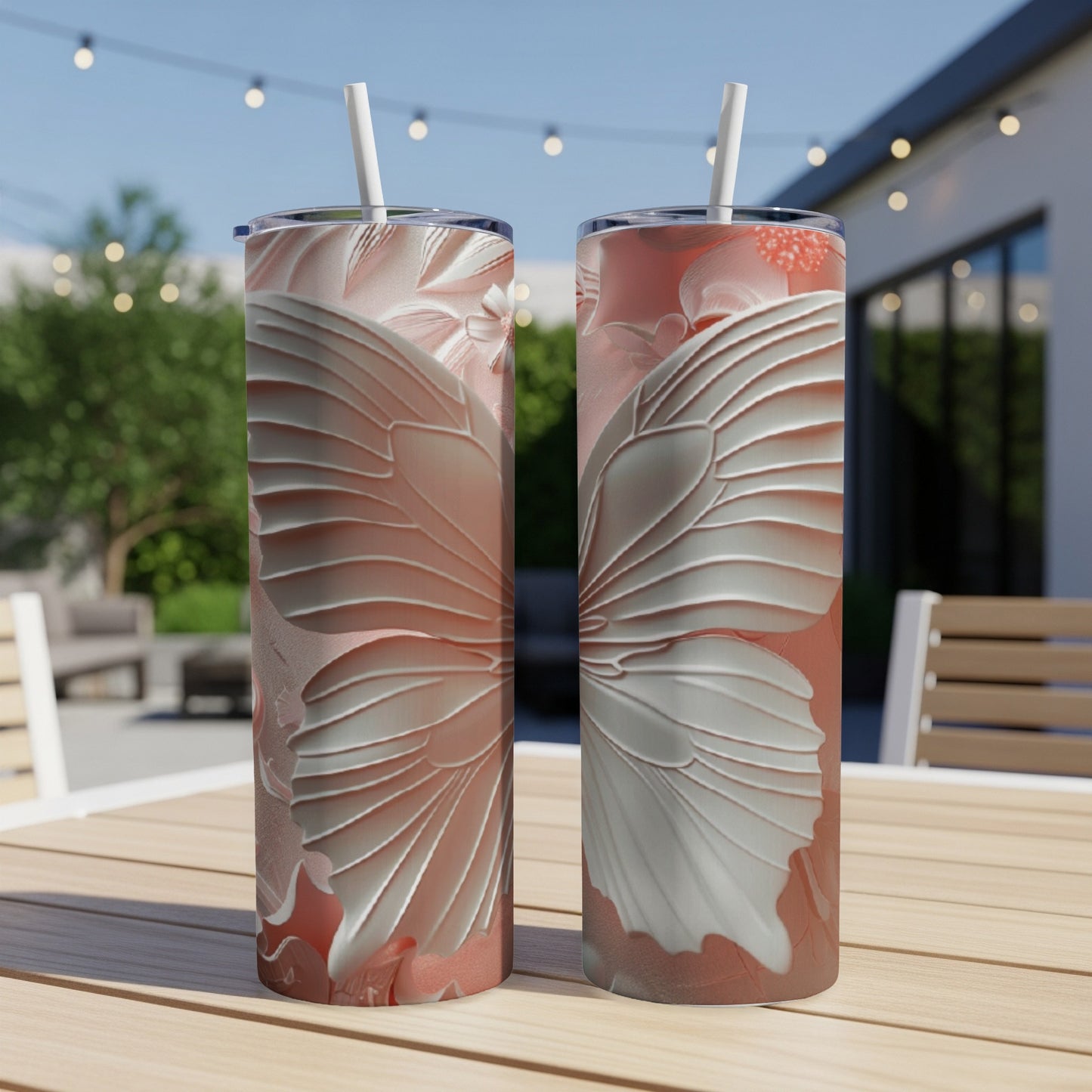 Two tall tumblers with a raised white butterfly wing design on a wooden table outdoors.