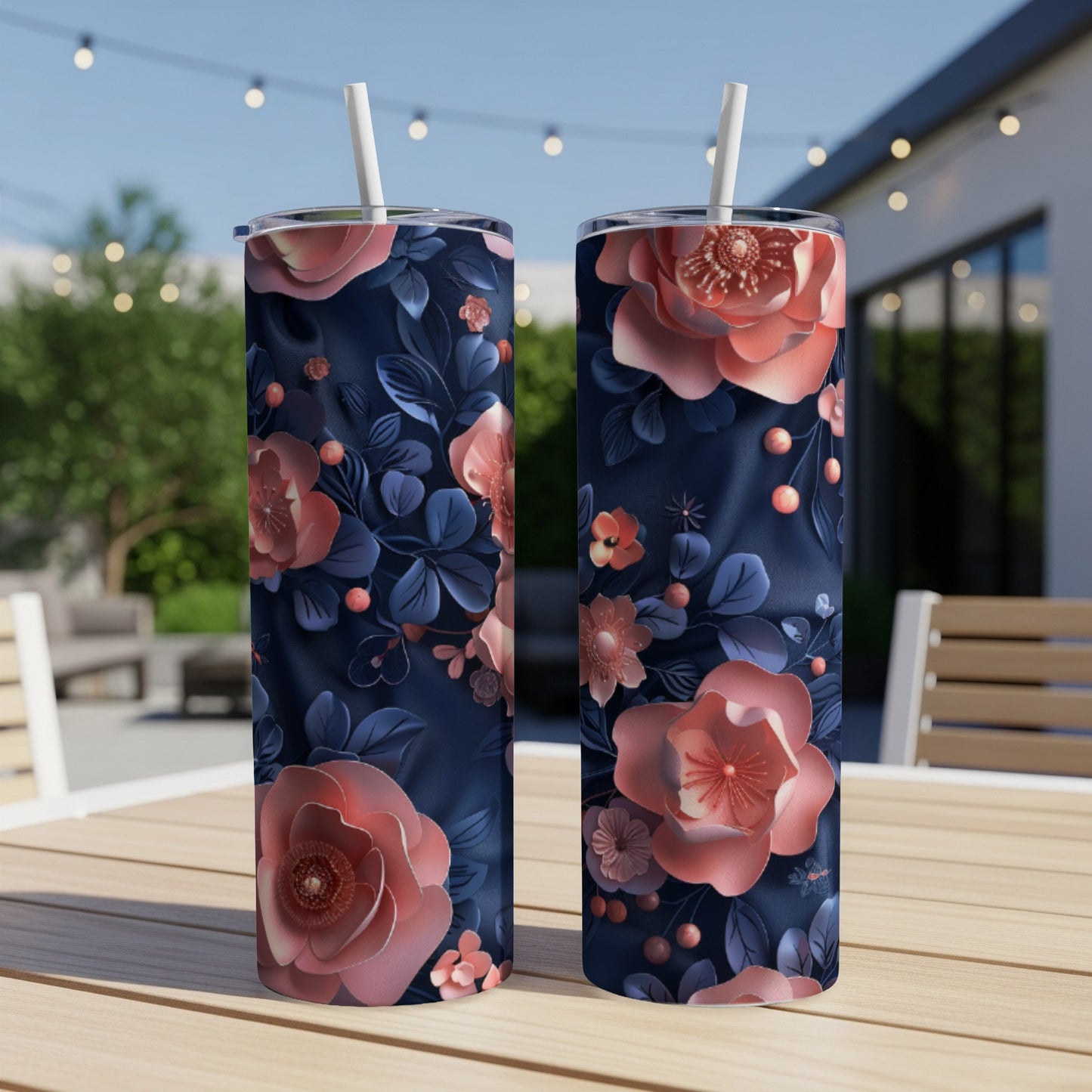Two dark blue tumblers with floral designs sit on a wooden table outdoors.
