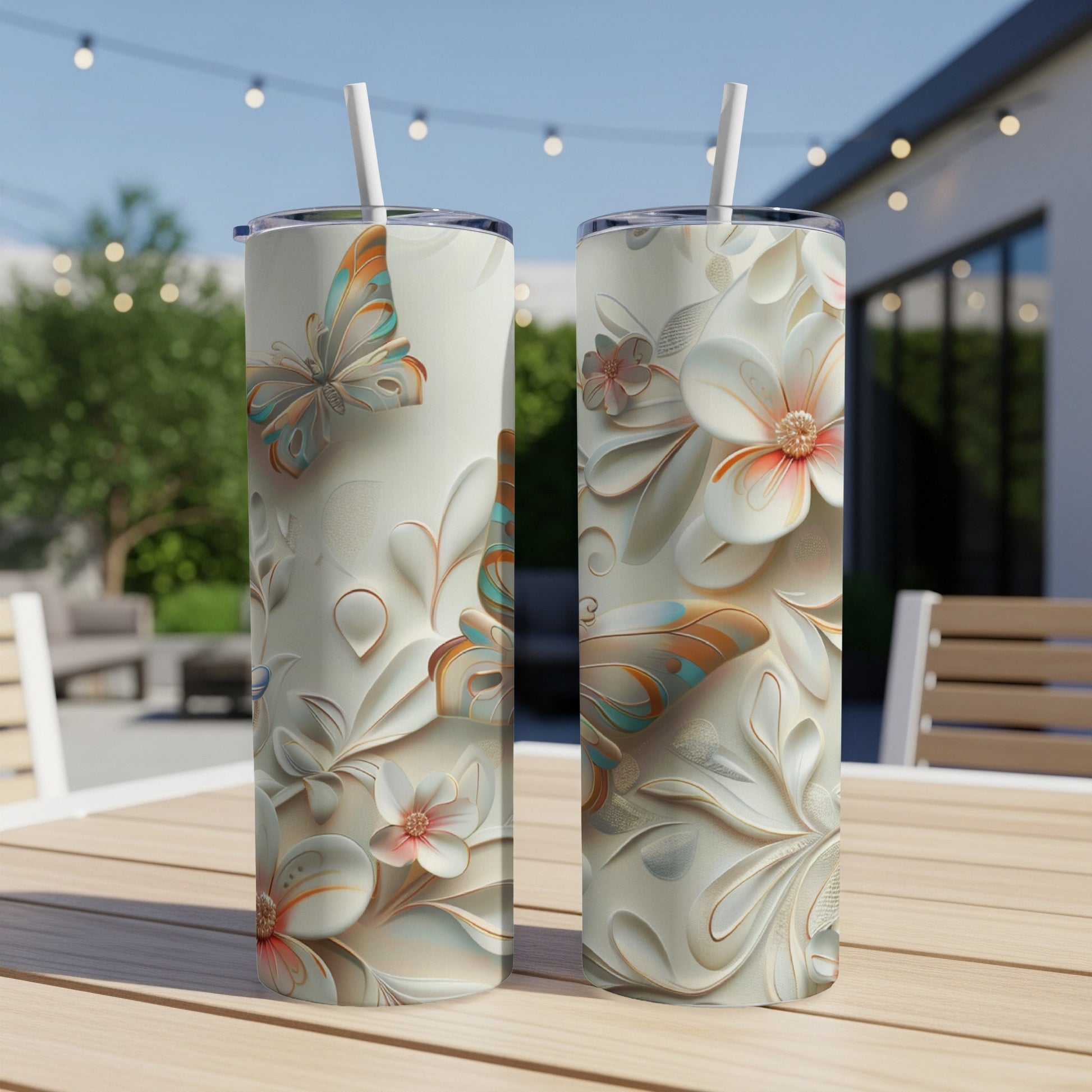 Two tall, cream-colored tumblers with butterfly and floral relief designs on a wooden table.