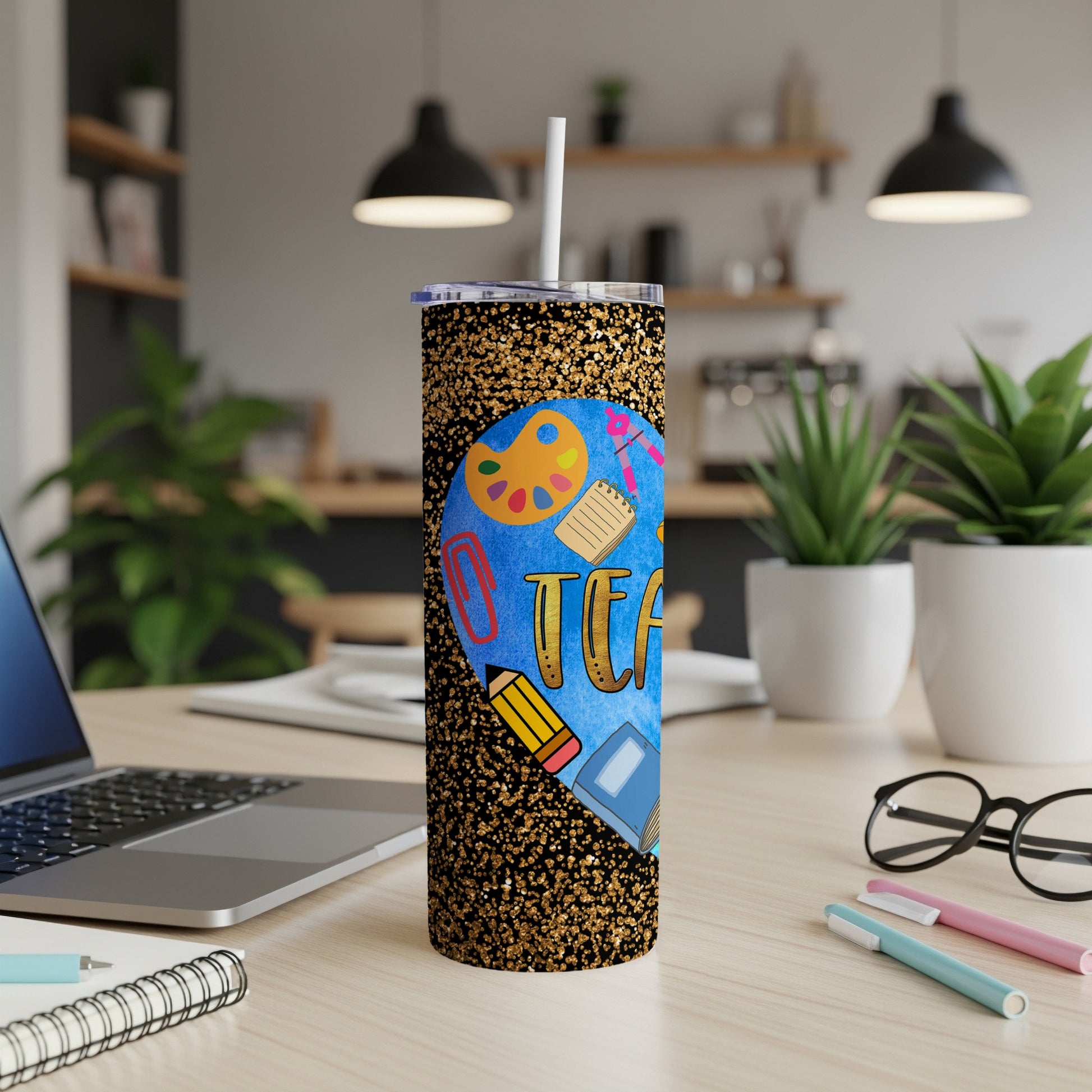 Gold glitter tumbler with "Teacher" text and school supplies on desk.