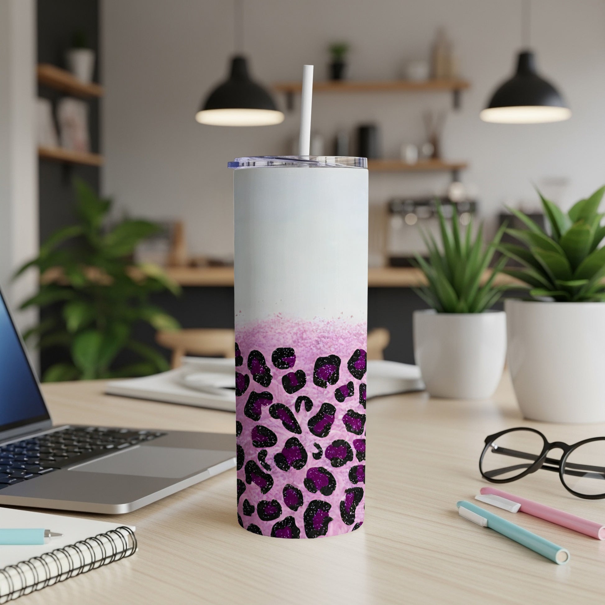White and pink leopard print tumbler with straw on a desk.