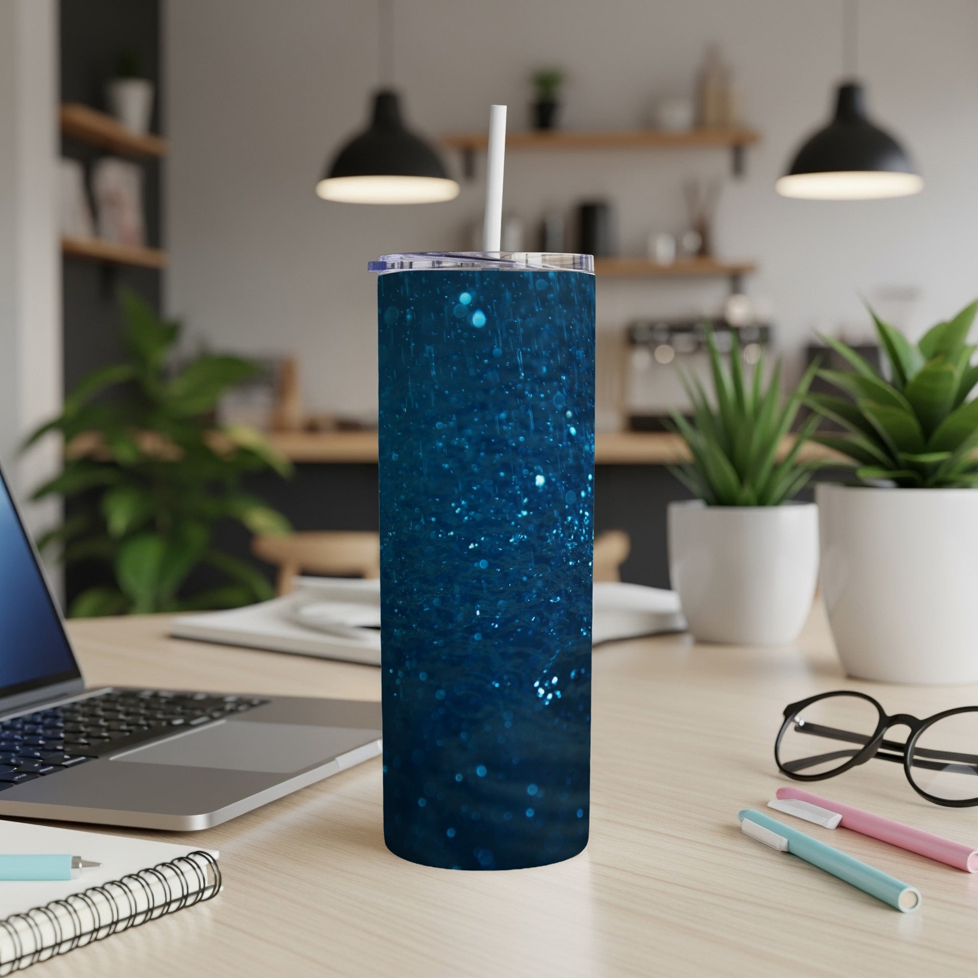 Blue glitter tumbler with white straw on a desk with a laptop.