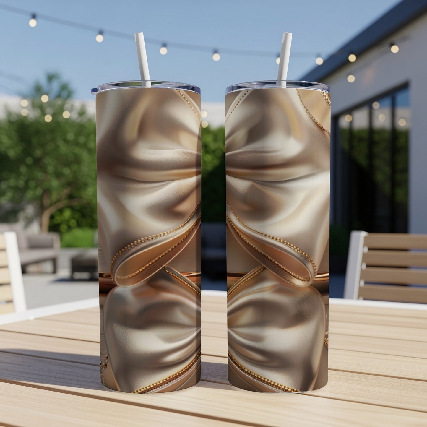 Two gold tumblers with chain and fabric design on a wooden table.