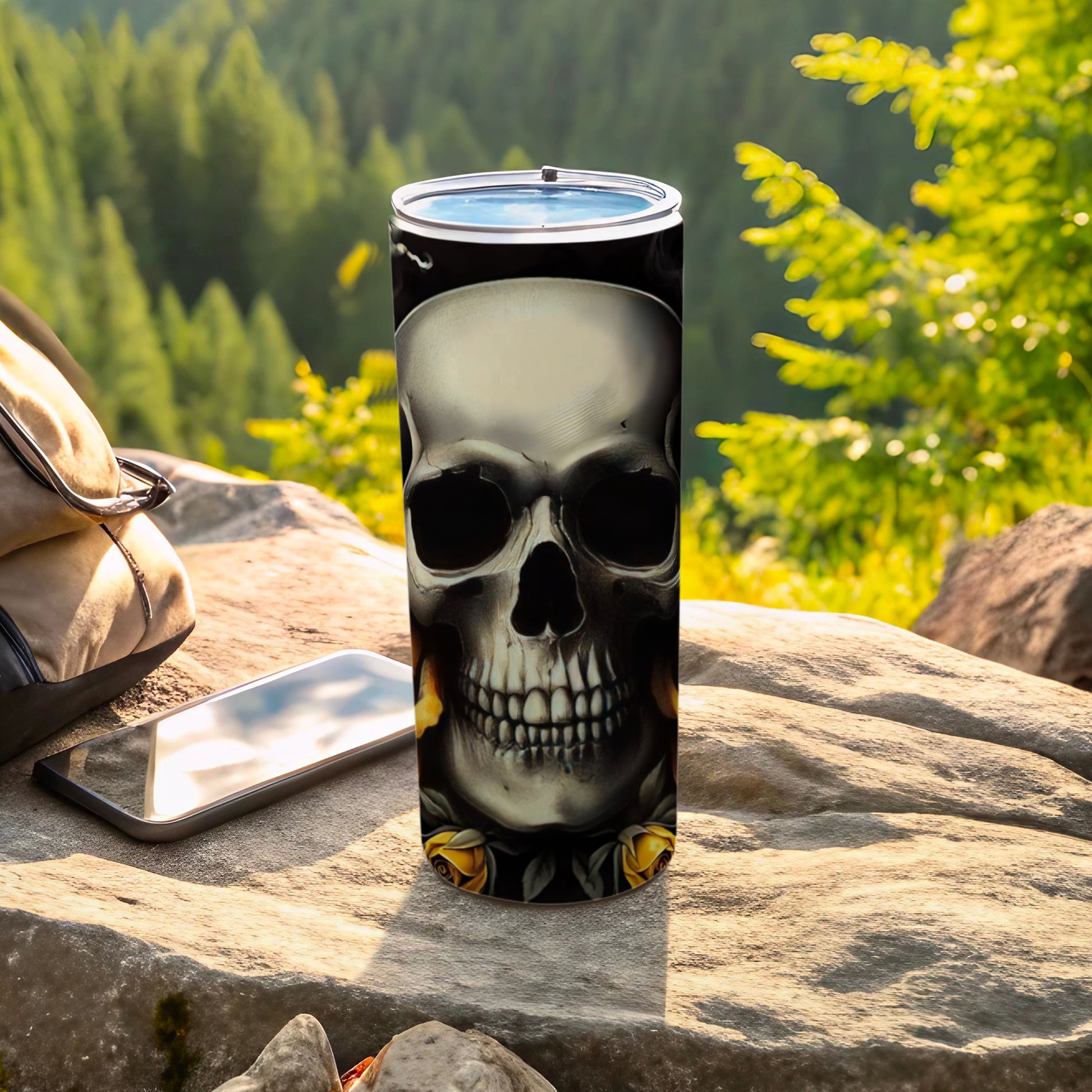 Skull and roses design on a black tumbler with phone and backpack.