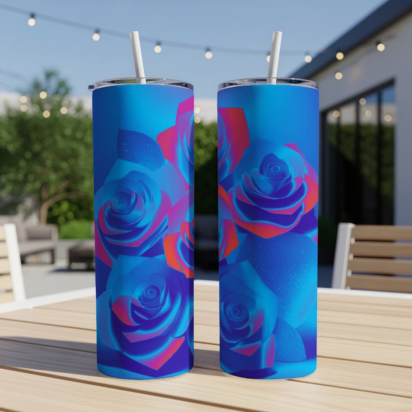 Two blue tumblers with rose designs sit on a table outdoors.