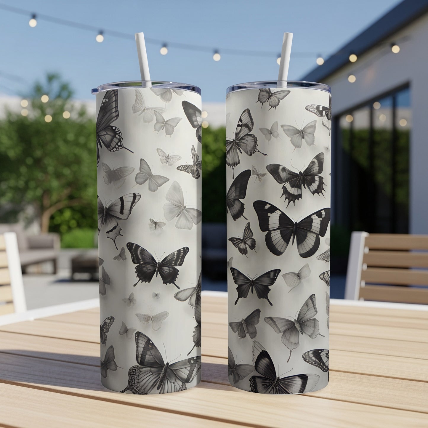 Two patterned tumblers with black and white butterfly designs on a table.
