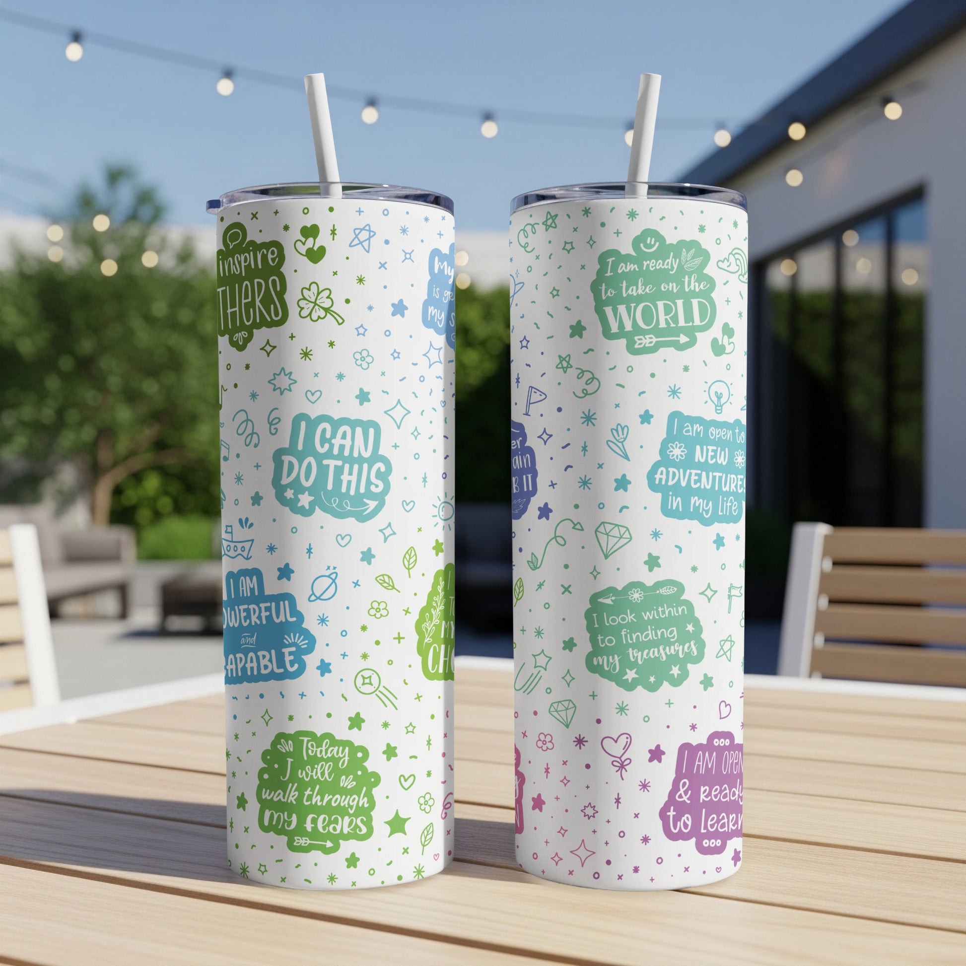 Two tumblers with motivational quotes and colorful illustrations on a table.