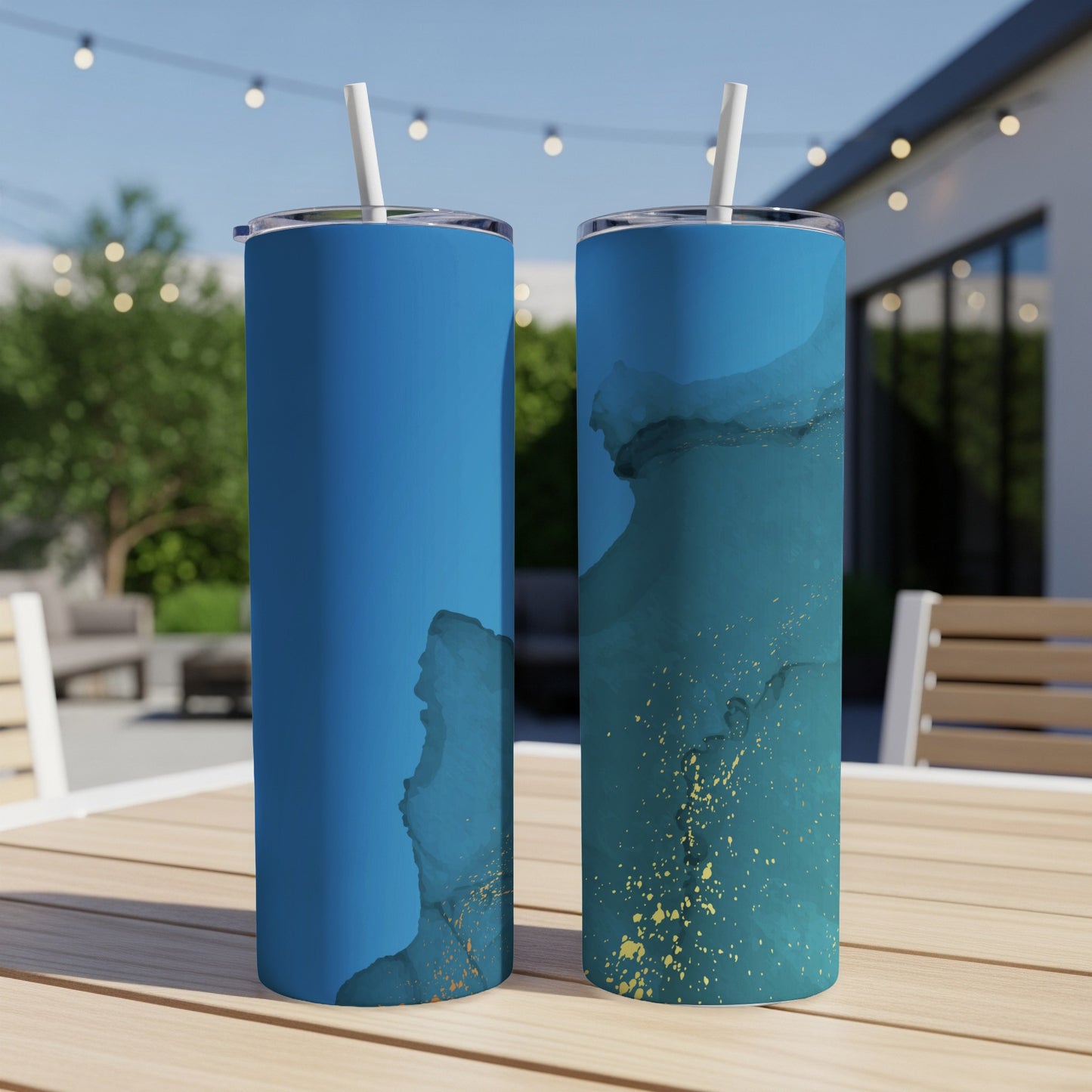 Two blue tumblers with teal and gold abstract design on a wooden table.
