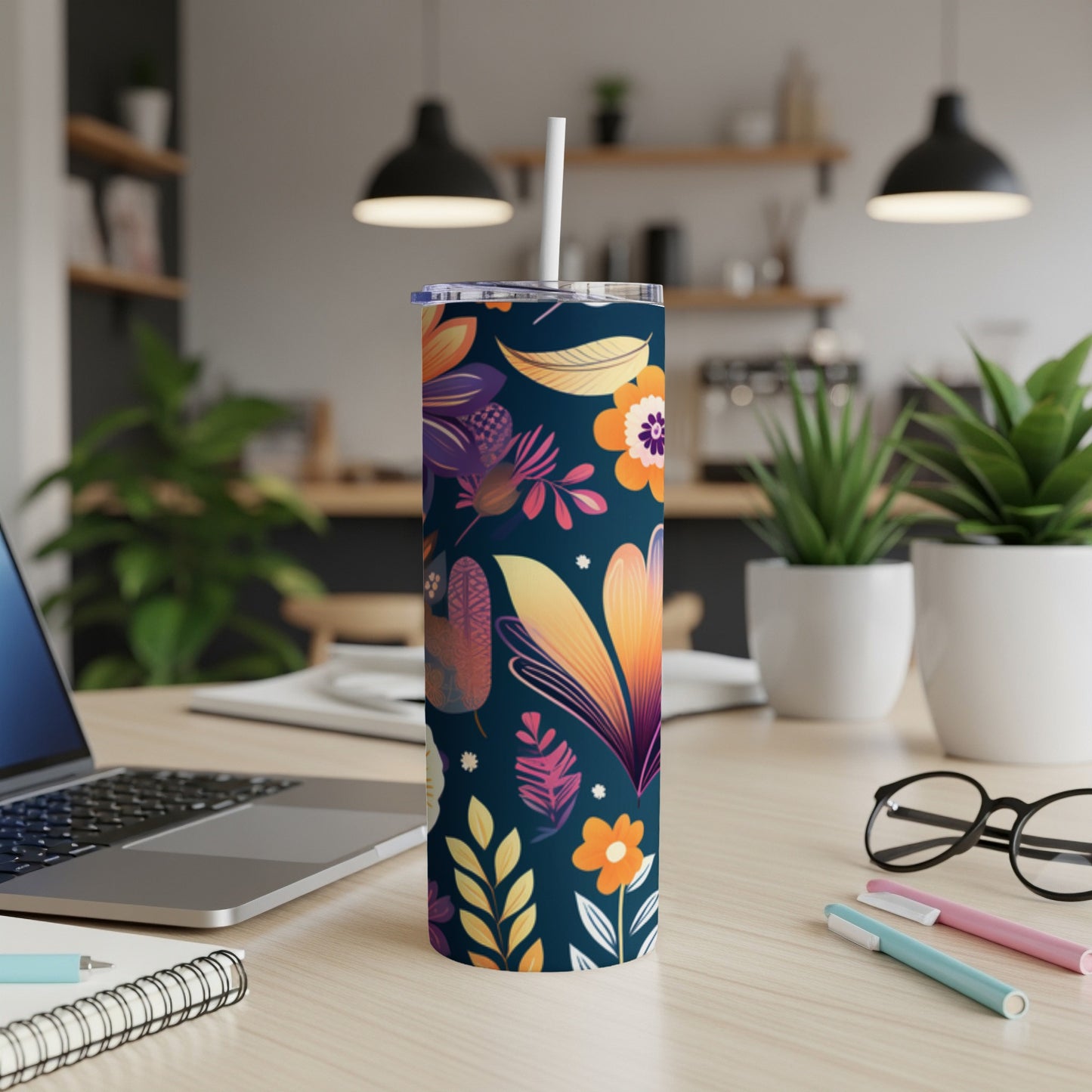 Dark blue tumbler with a colorful floral and leaf pattern, on a desk.