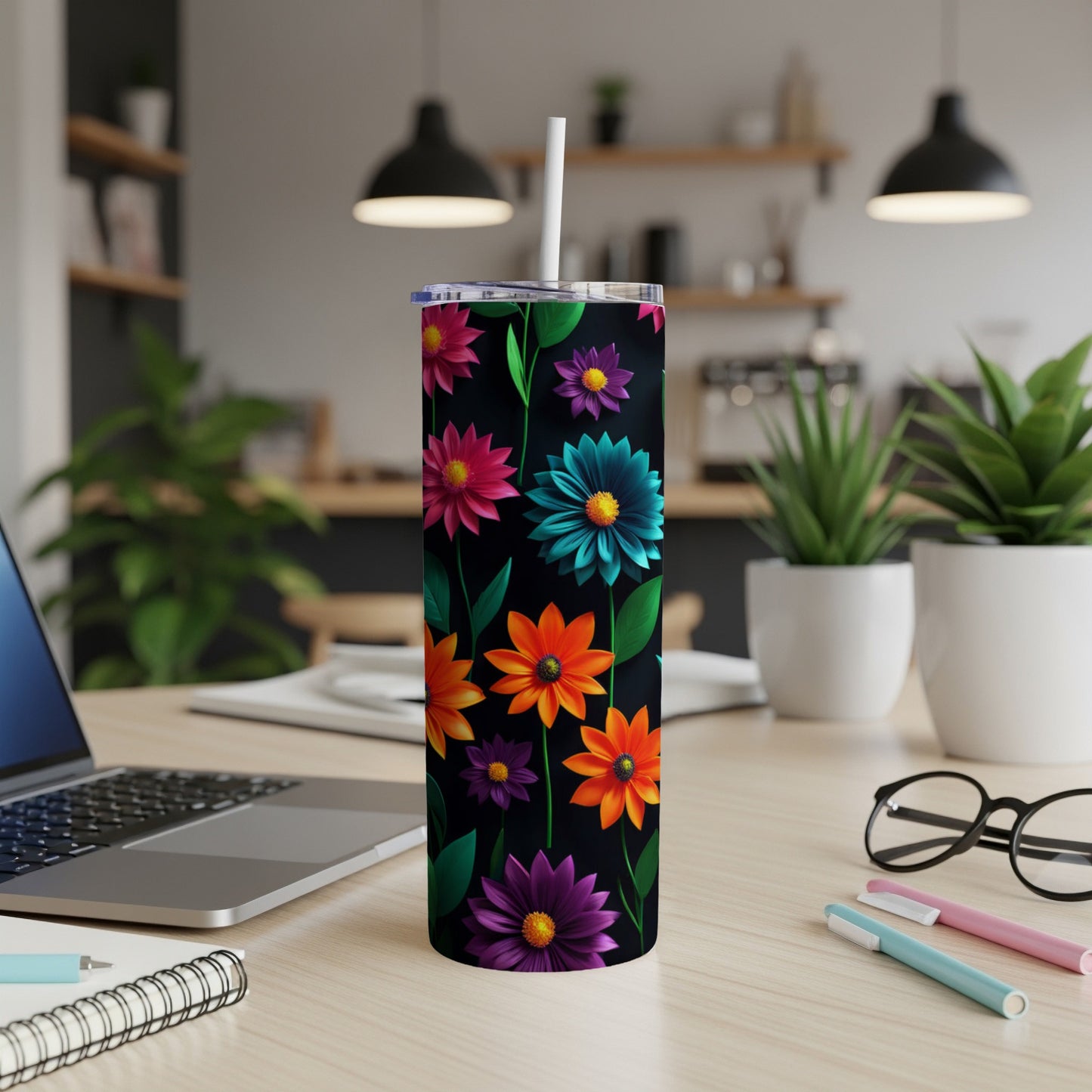 Black tumbler with colorful floral pattern and white straw on desk.
