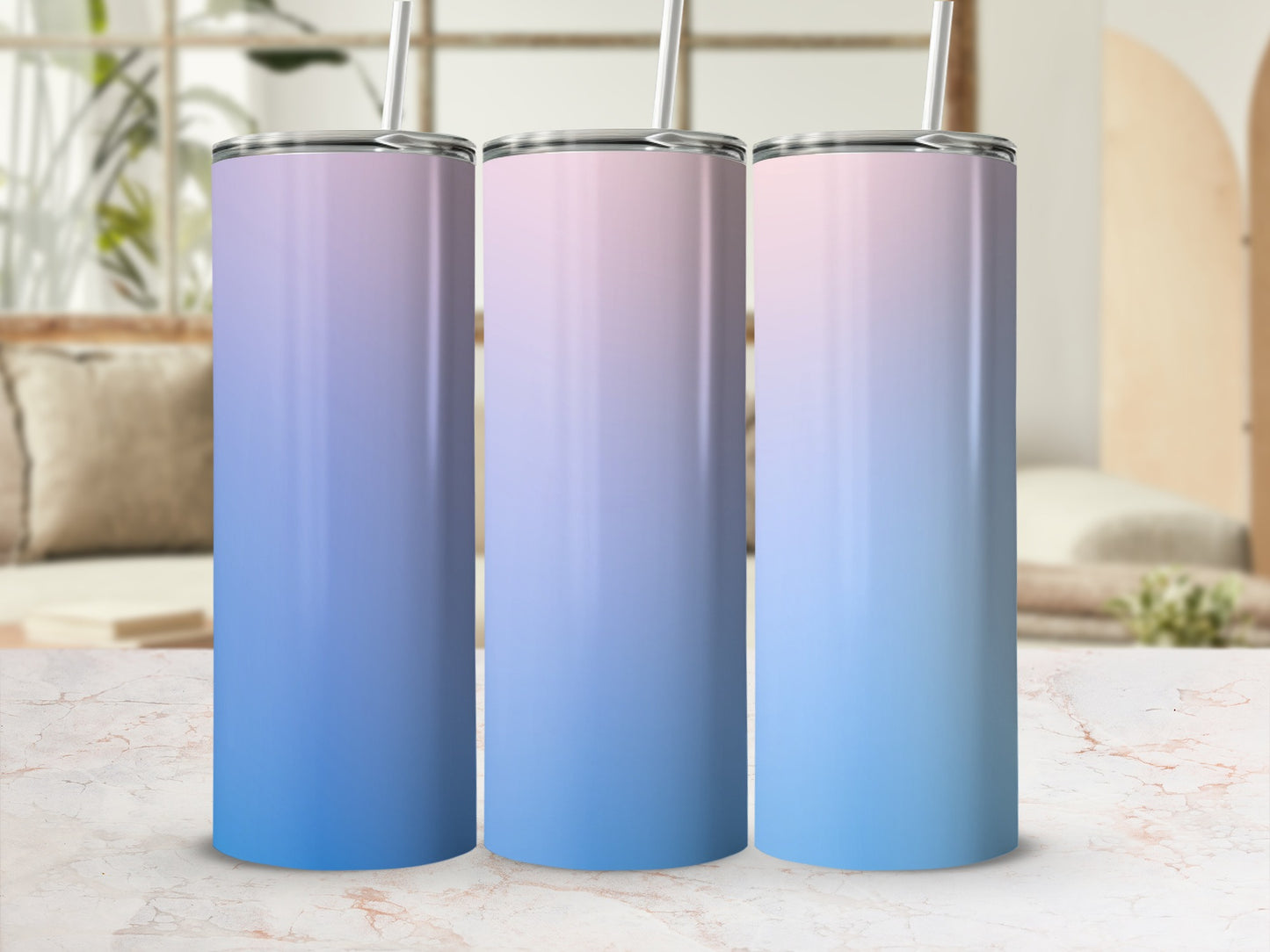 Three tall tumblers with a gradient of blue and pink sit on a marble surface.
