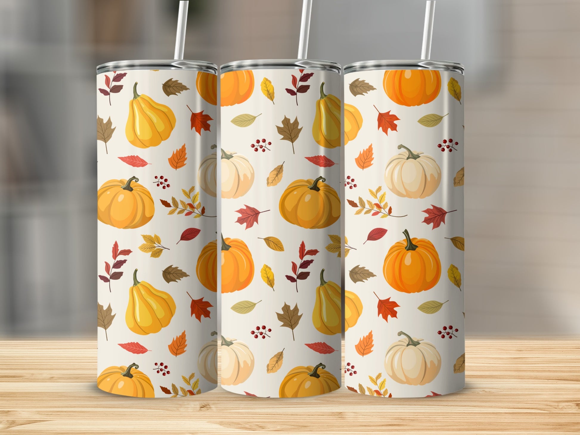 Three tumblers with a fall pumpkin and leaf pattern on a wooden surface.