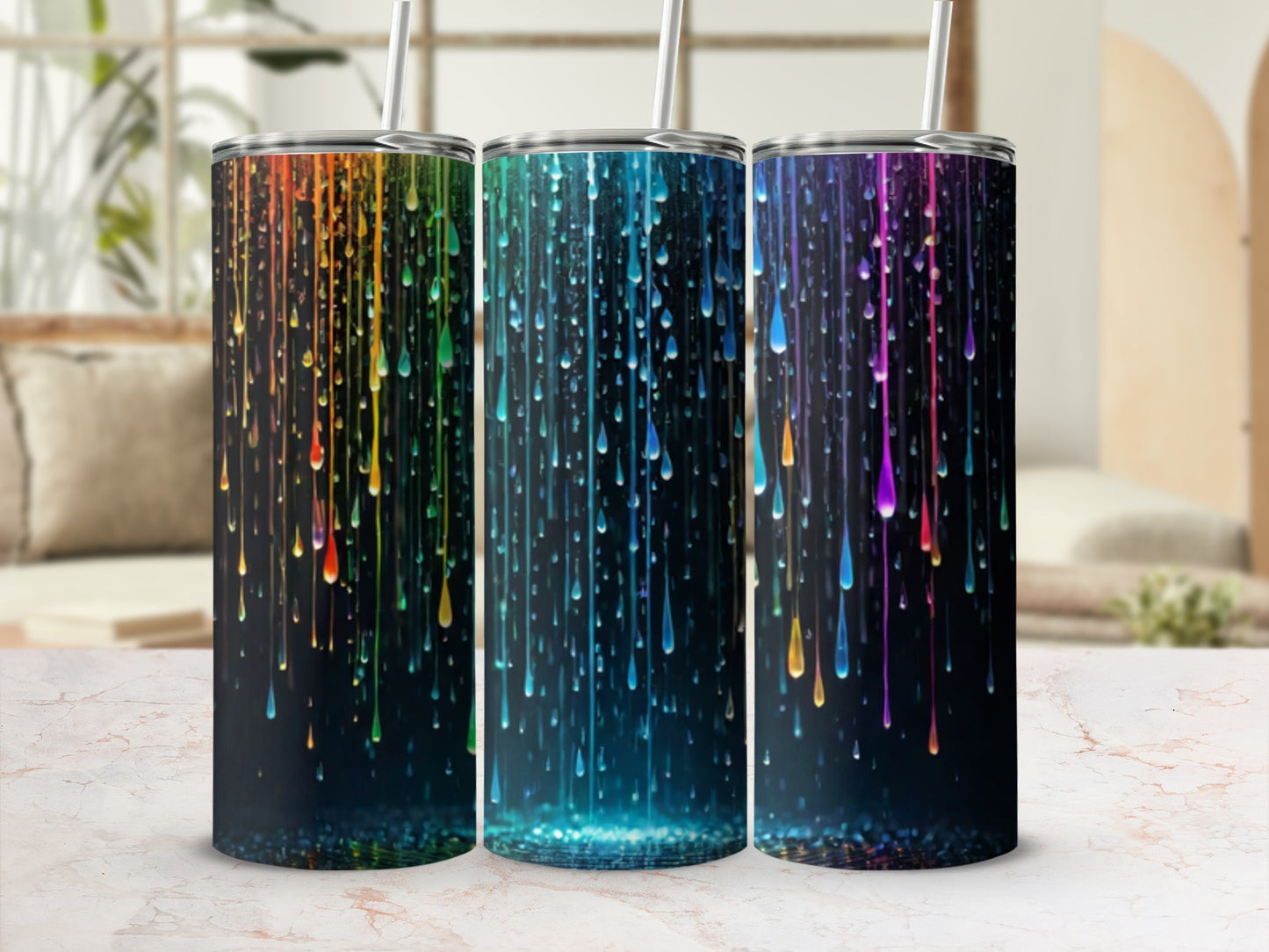 Three tumblers with colorful dripping paint design on a marble countertop.