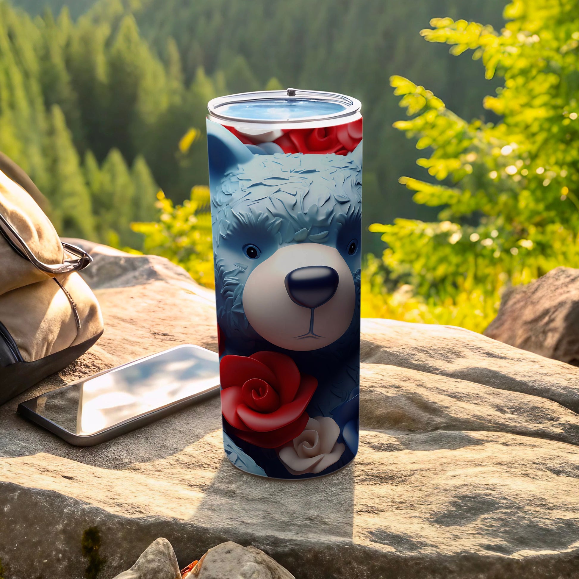 Blue teddy bear tumbler with red roses, displayed outdoors.