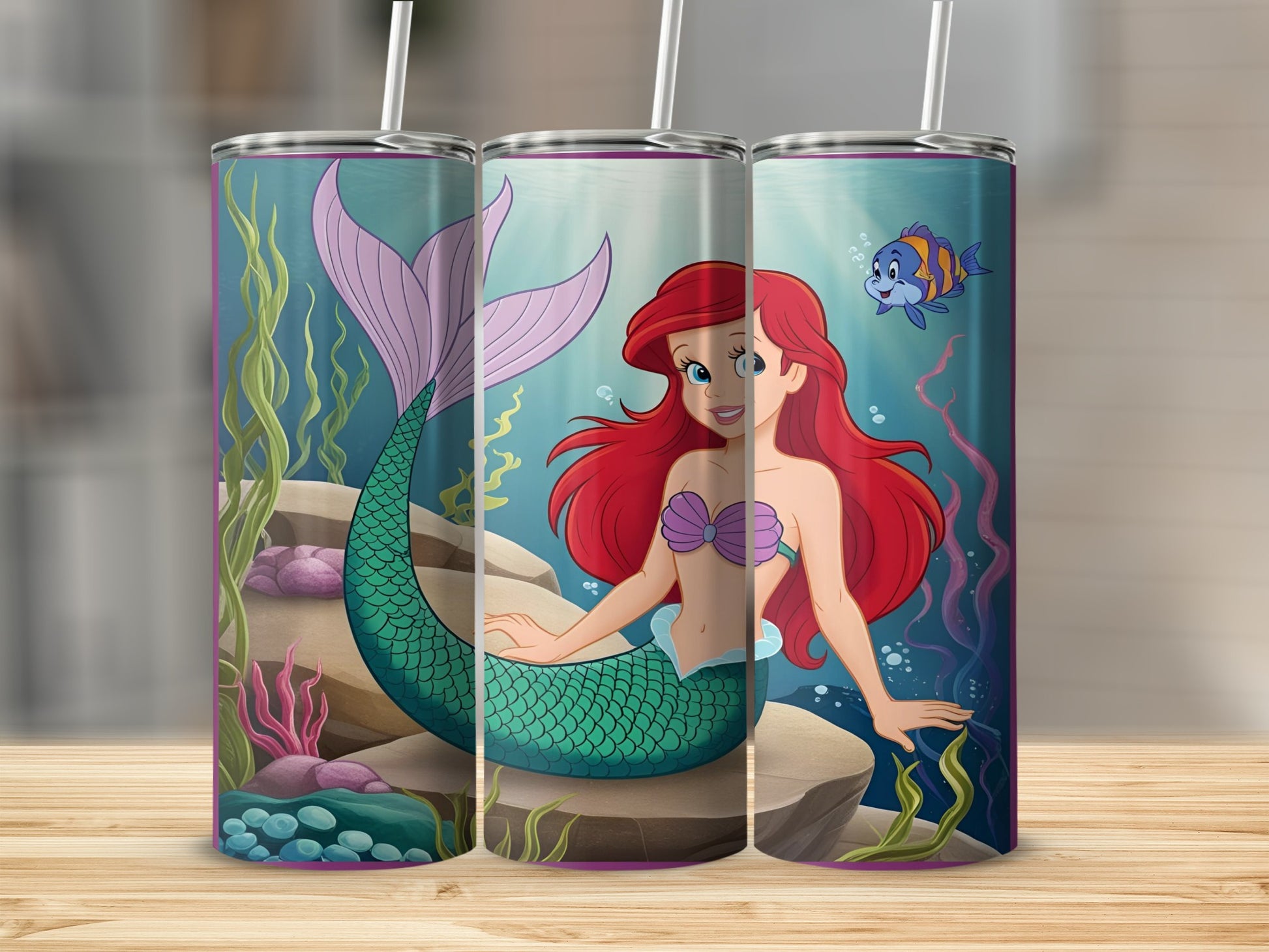 Ariel the mermaid with a small blue fish in an underwater scene on three tumblers.