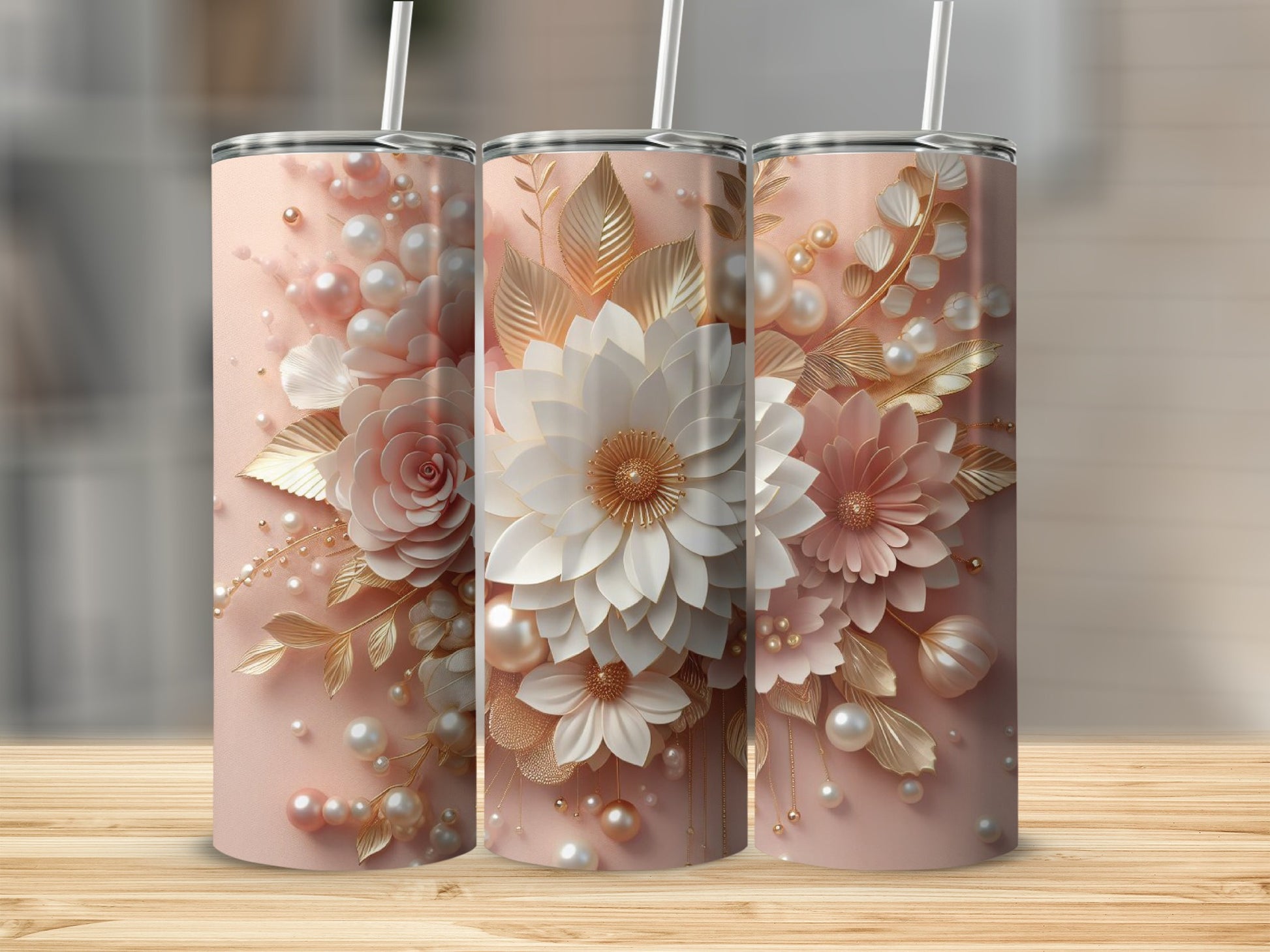 Three pink tumblers with floral and pearl designs, on a wooden surface.