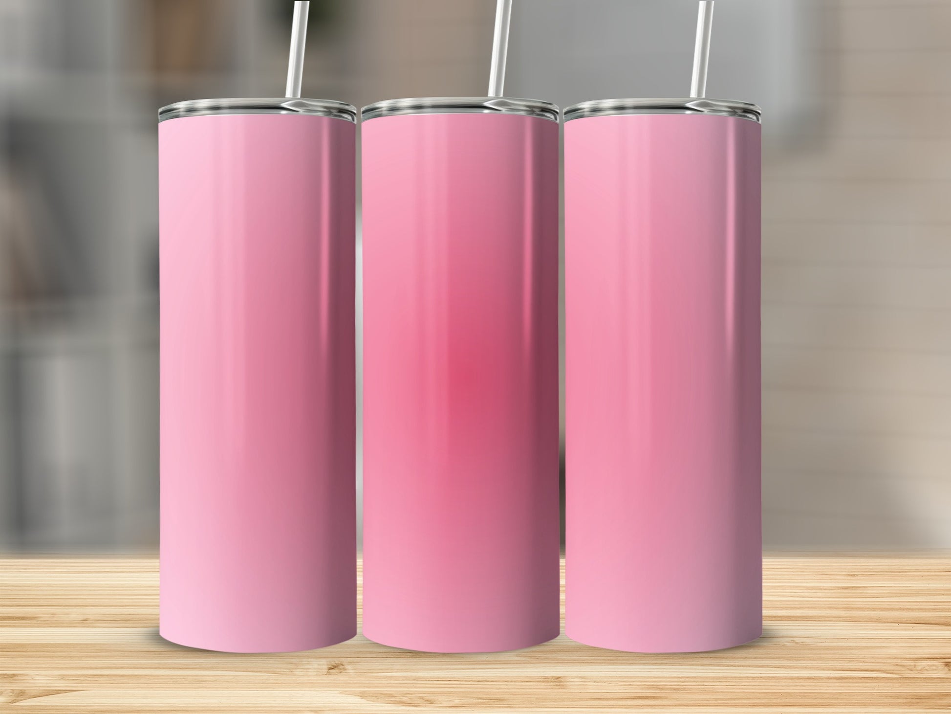 Three pink gradient tumblers with straws on a wooden surface.
