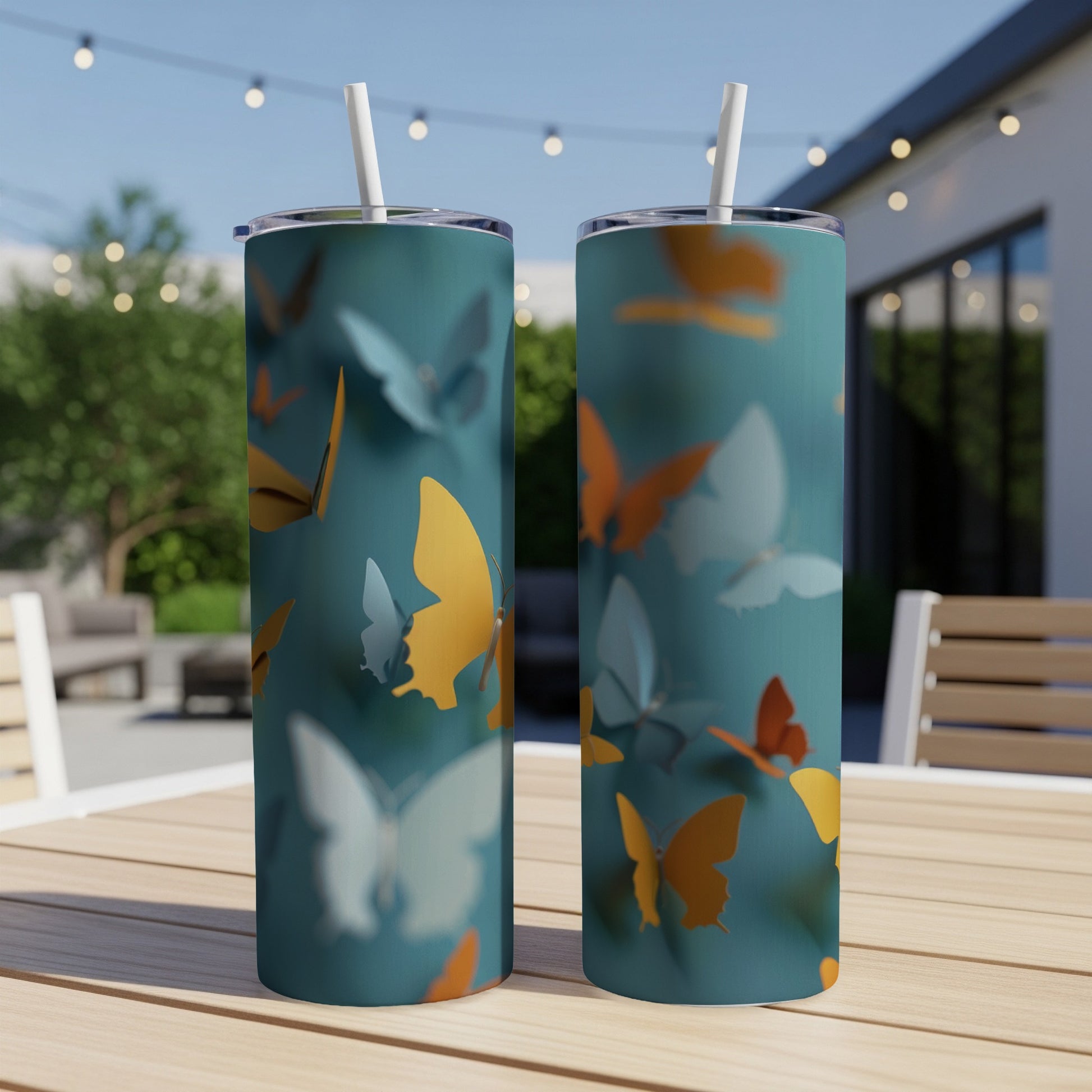 Two teal tumblers with orange and yellow butterflies, straw in each.