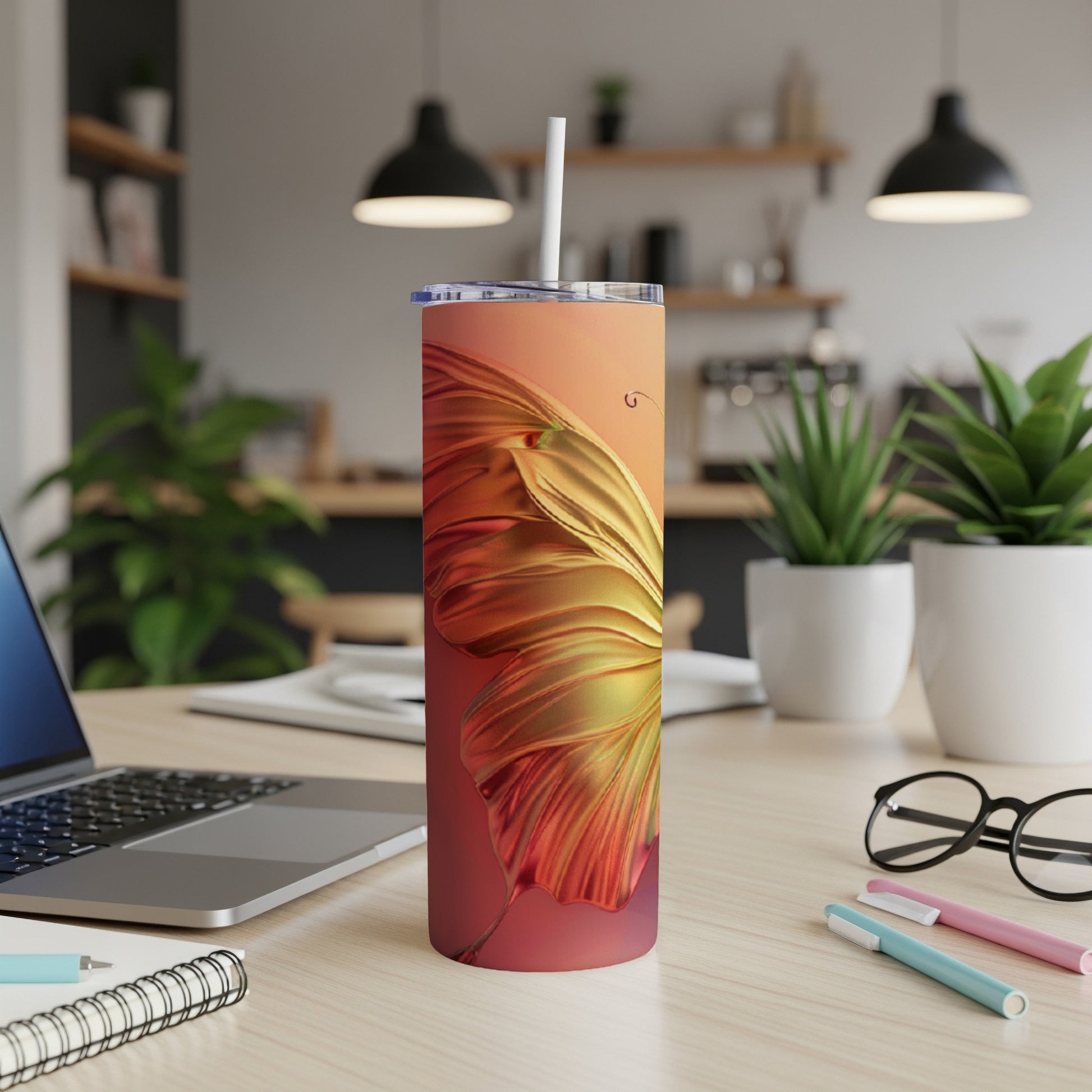 Golden butterfly wing pattern on a slim, white tumbler with a straw.