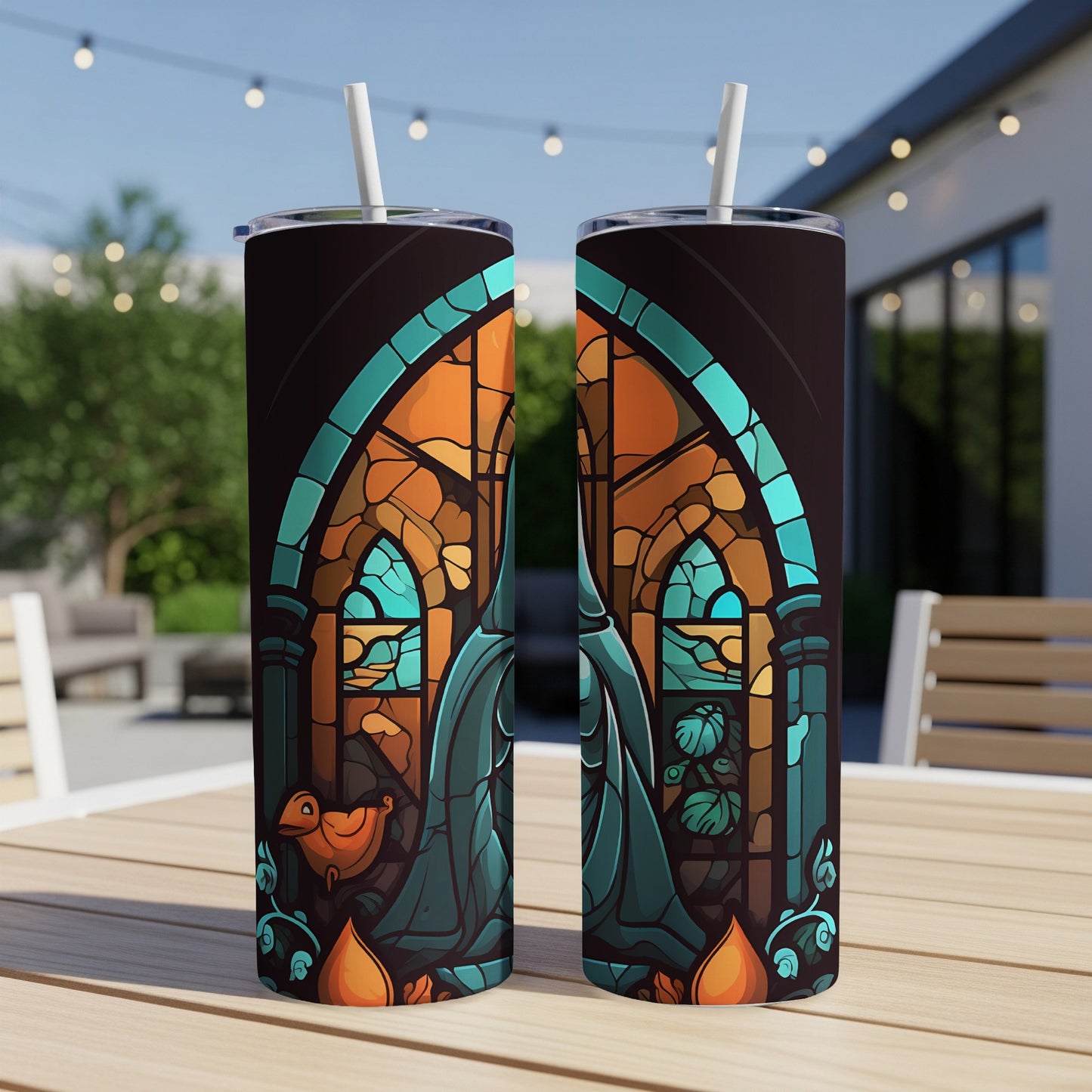 Two stained-glass patterned tumblers with straws on a wooden table.