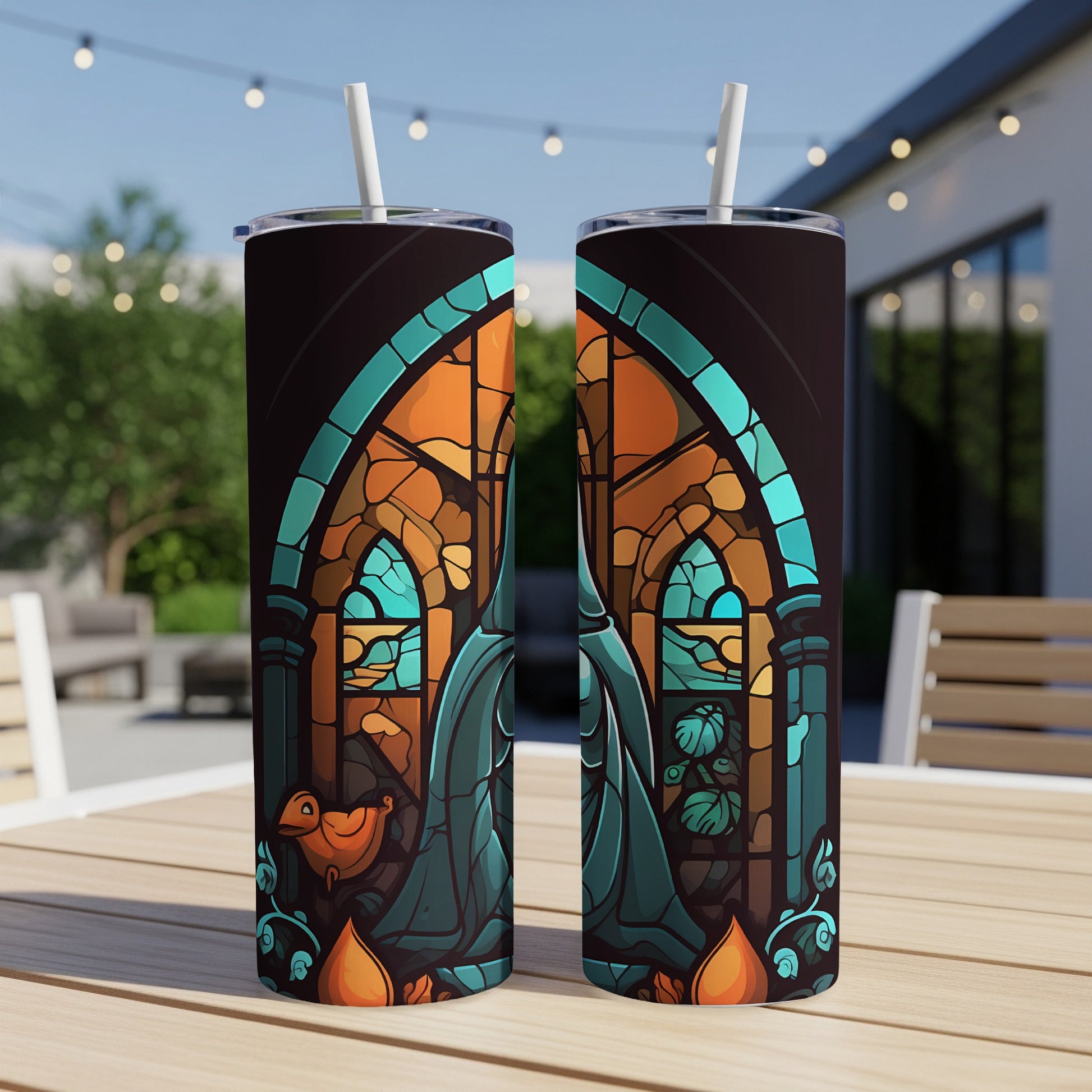Two stained-glass patterned tumblers with straws on a wooden table.