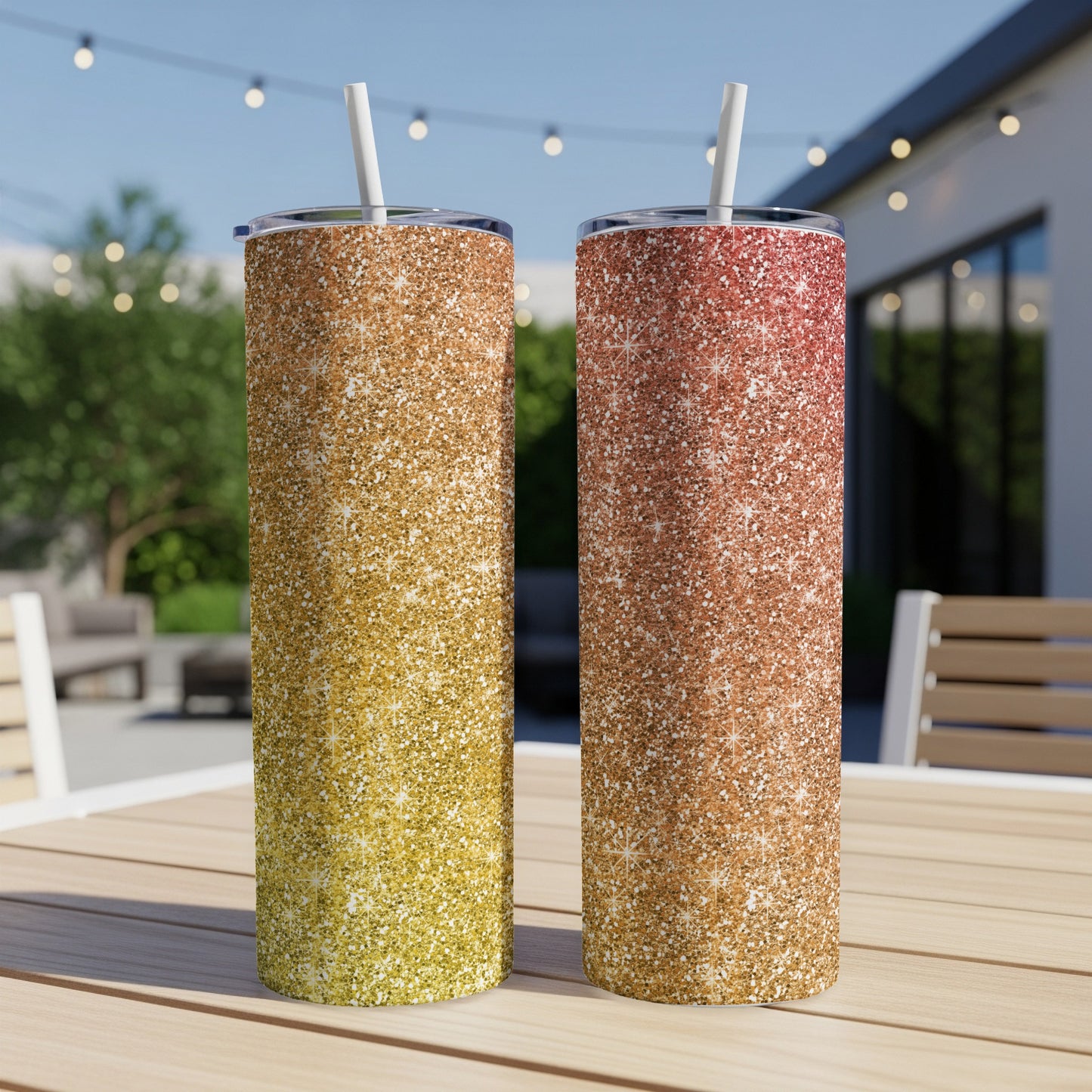 Two glitter tumblers, one yellow-gold, one rose-gold, with straws sit on a table.