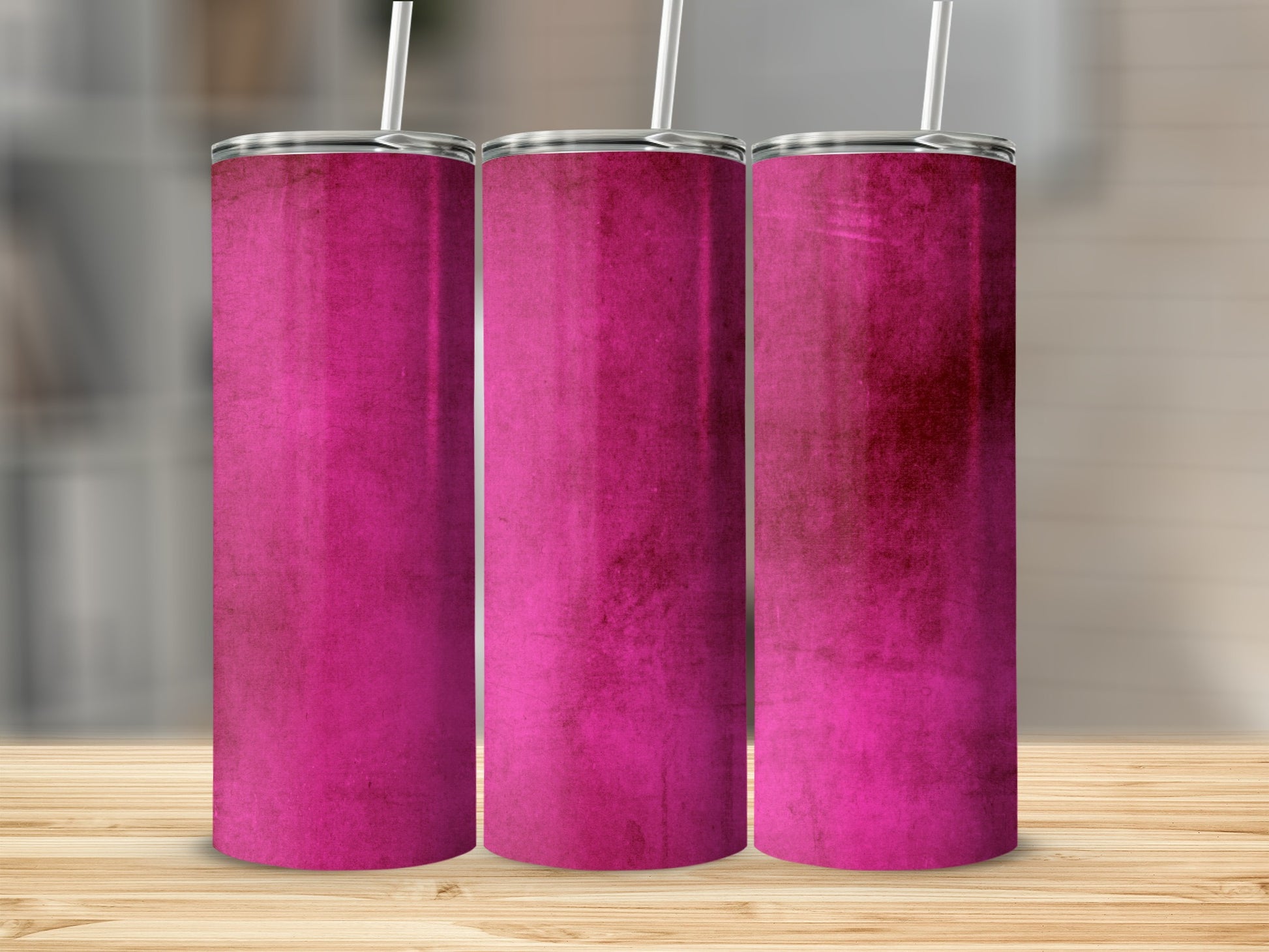 Three magenta tumblers with straws on a wooden surface.