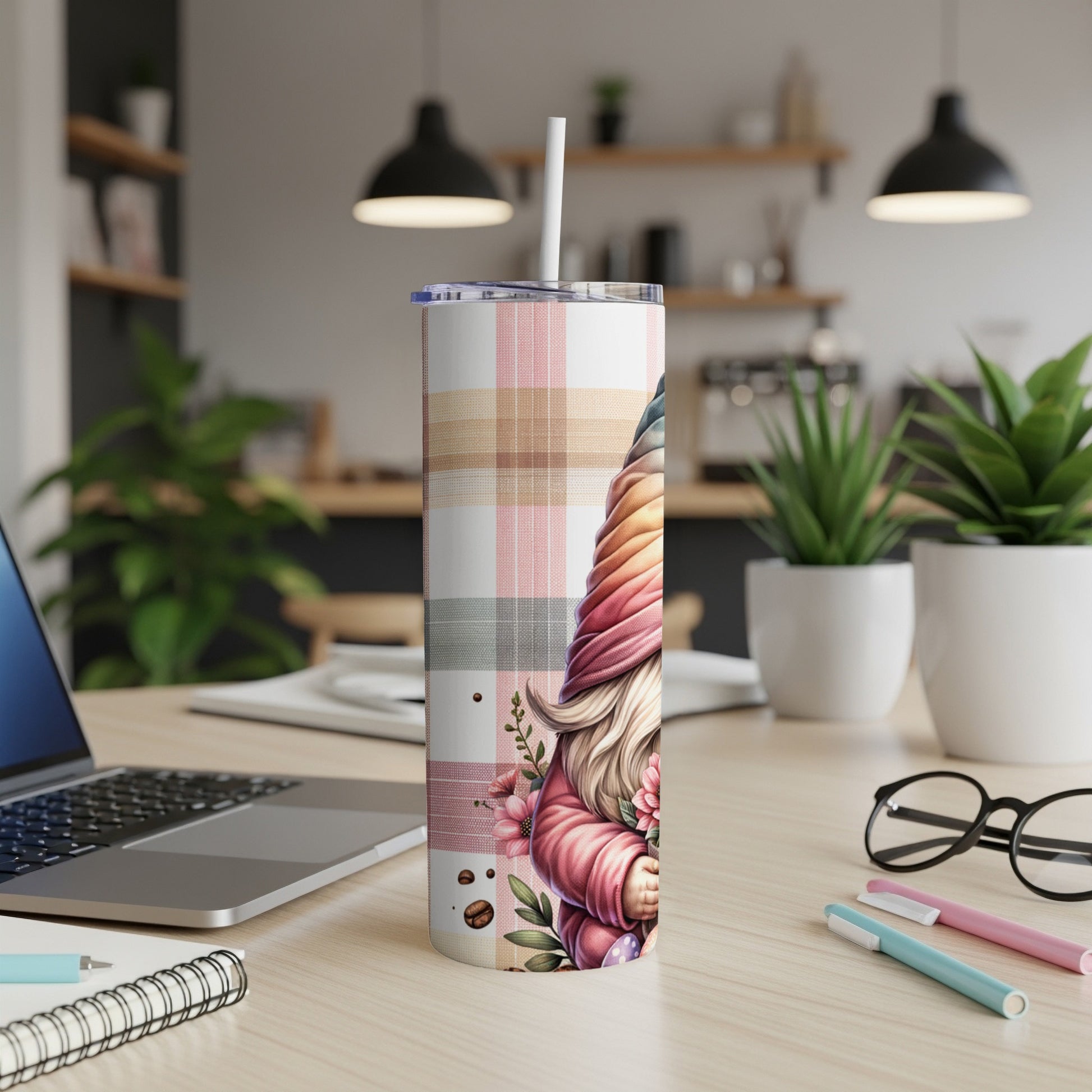 Gnome tumbler with pink and plaid pattern and floral accents on a desk.