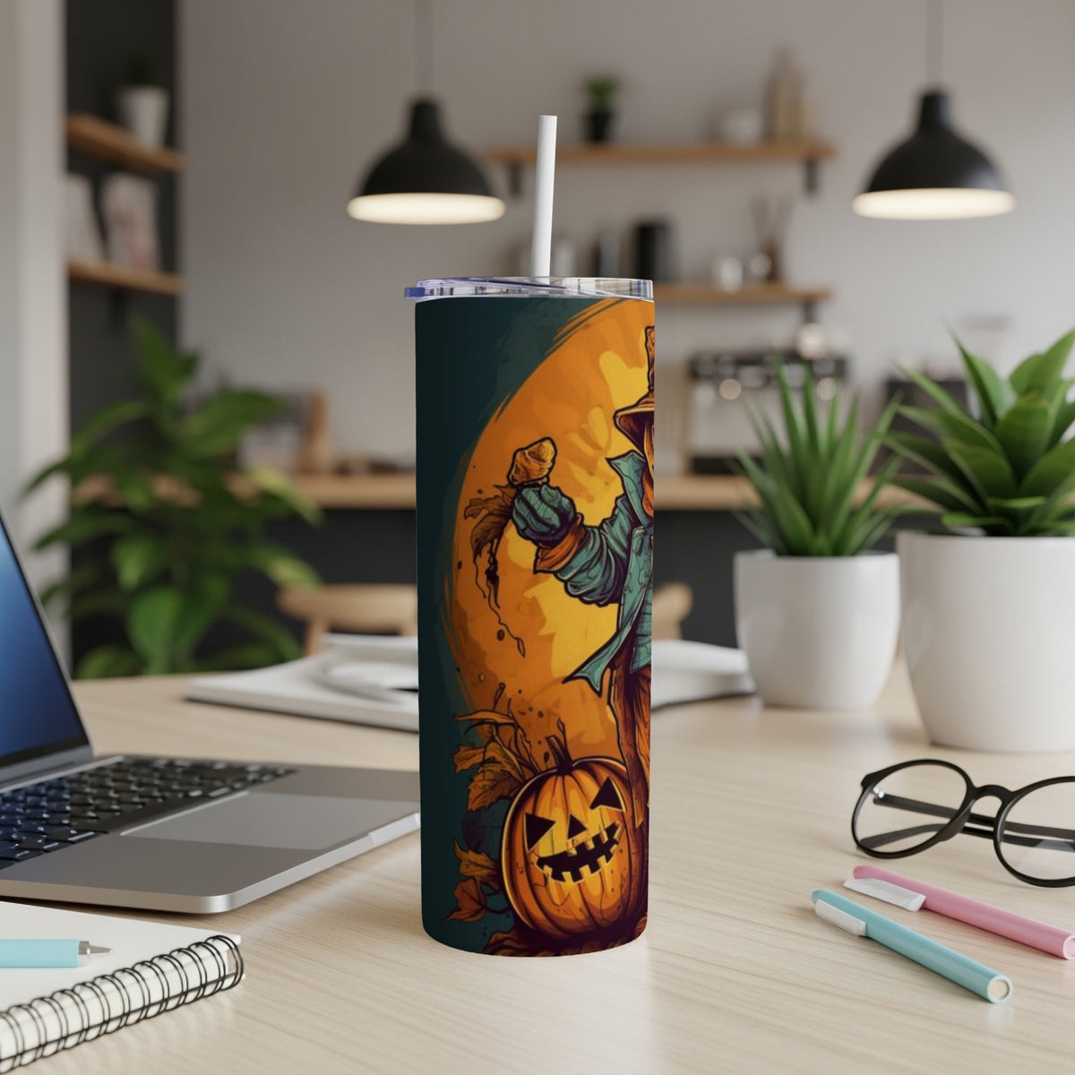 Tumbler with scarecrow and jack-o'-lantern Halloween design, on a desk.