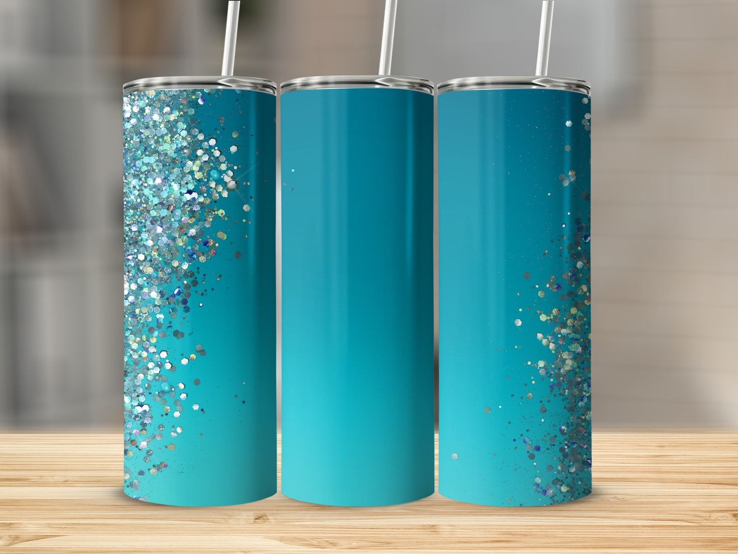 Three teal tumblers with glitter accents and straws sit on a wooden surface.