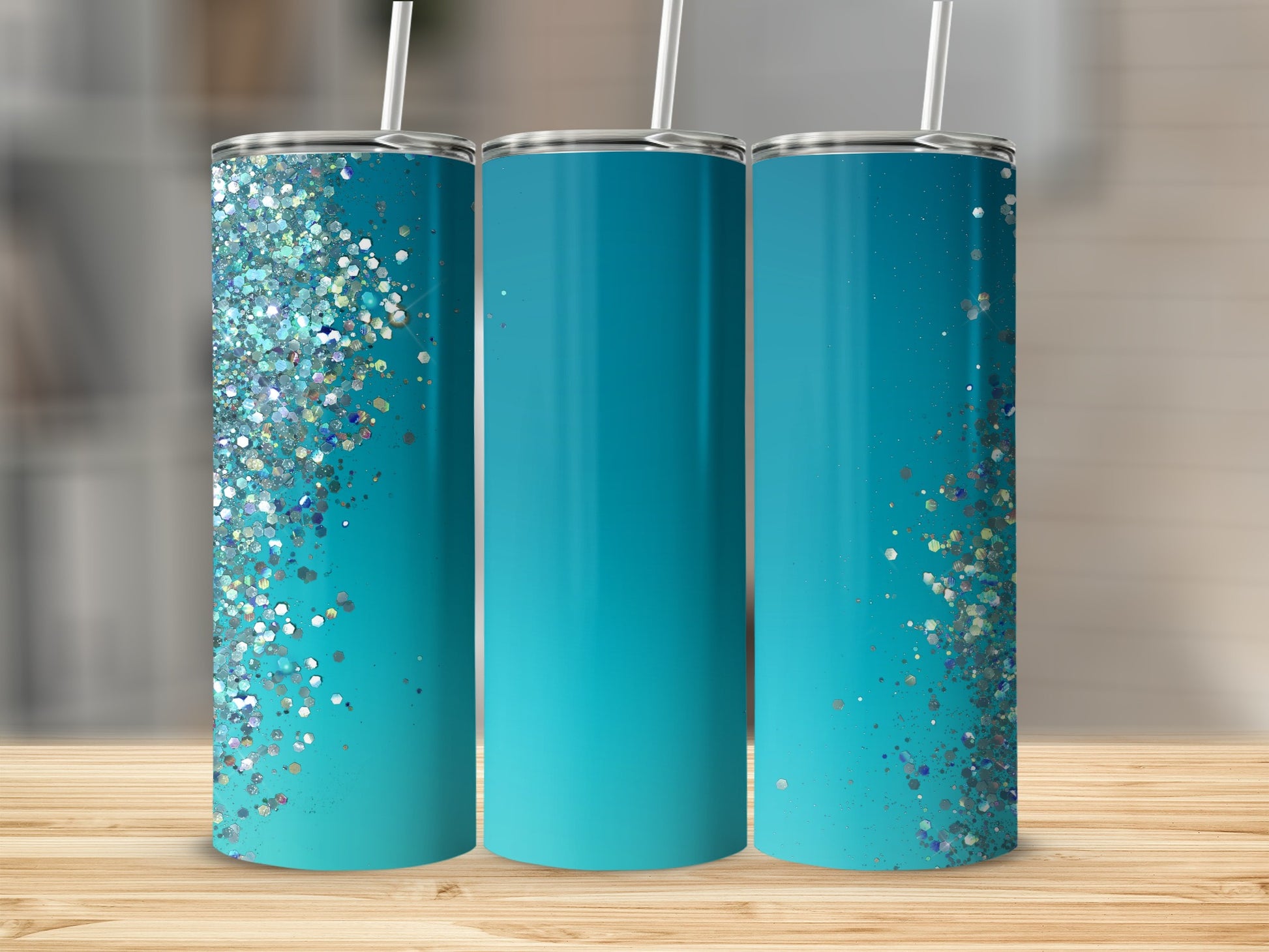 Three teal tumblers with glitter accents and straws sit on a wooden surface.