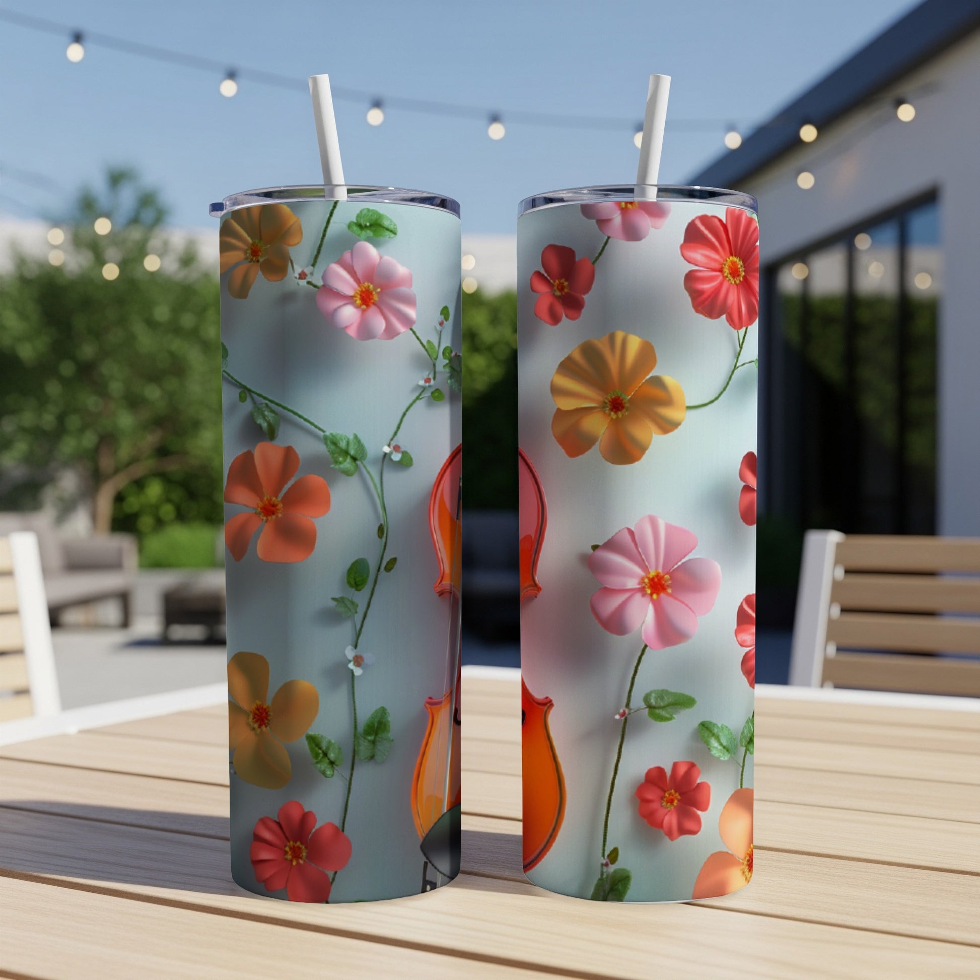 Two tall tumblers with colorful floral designs and straws on a wooden table.