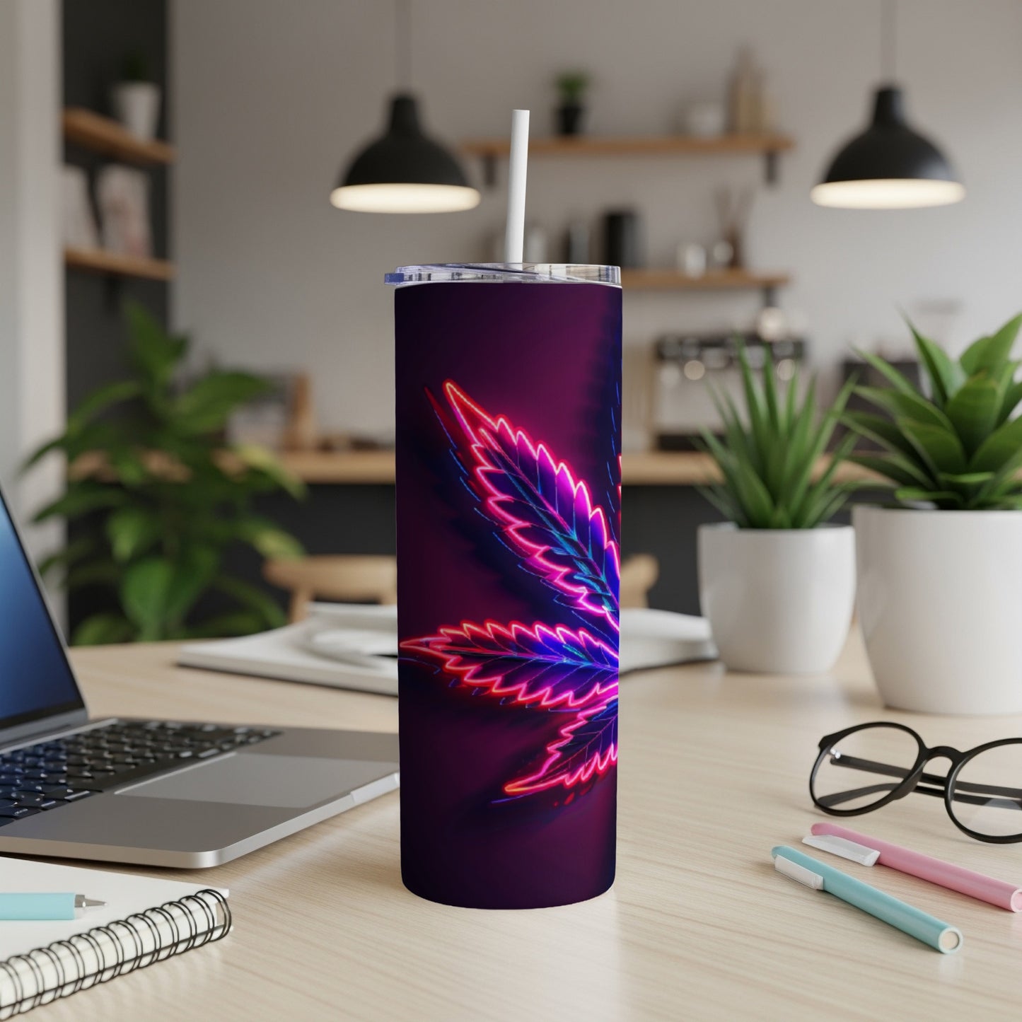 Purple tumbler with neon cannabis leaf design on a desk.