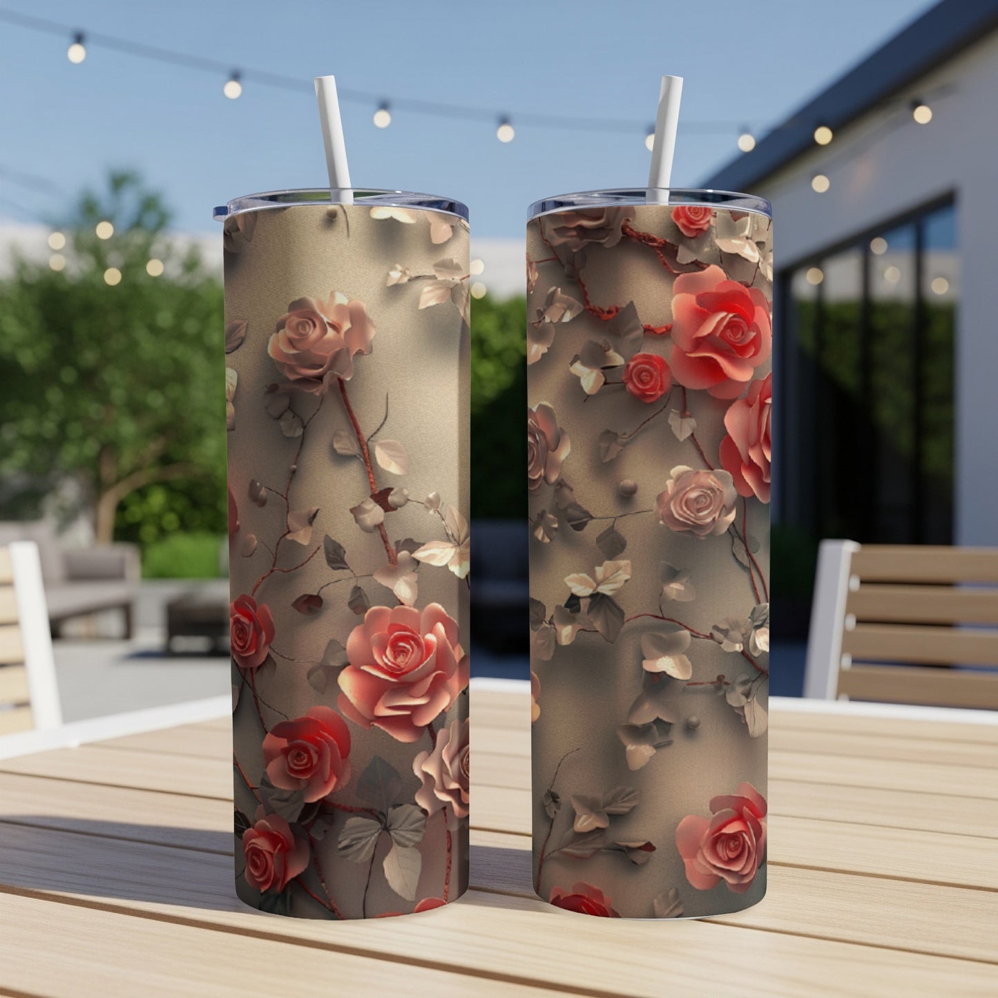 Two floral tumblers with pink roses and vines on a patio table.