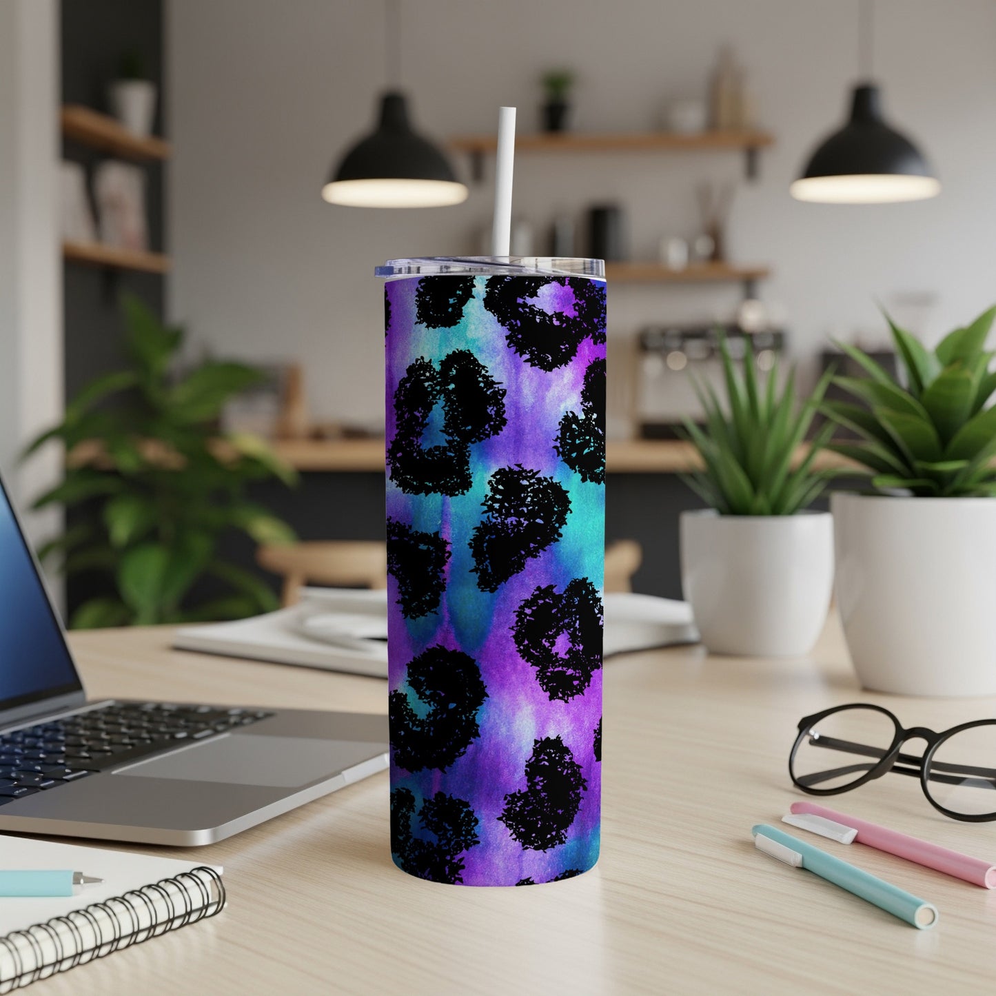 Tumbler with purple, teal, and black leopard print and a white straw.
