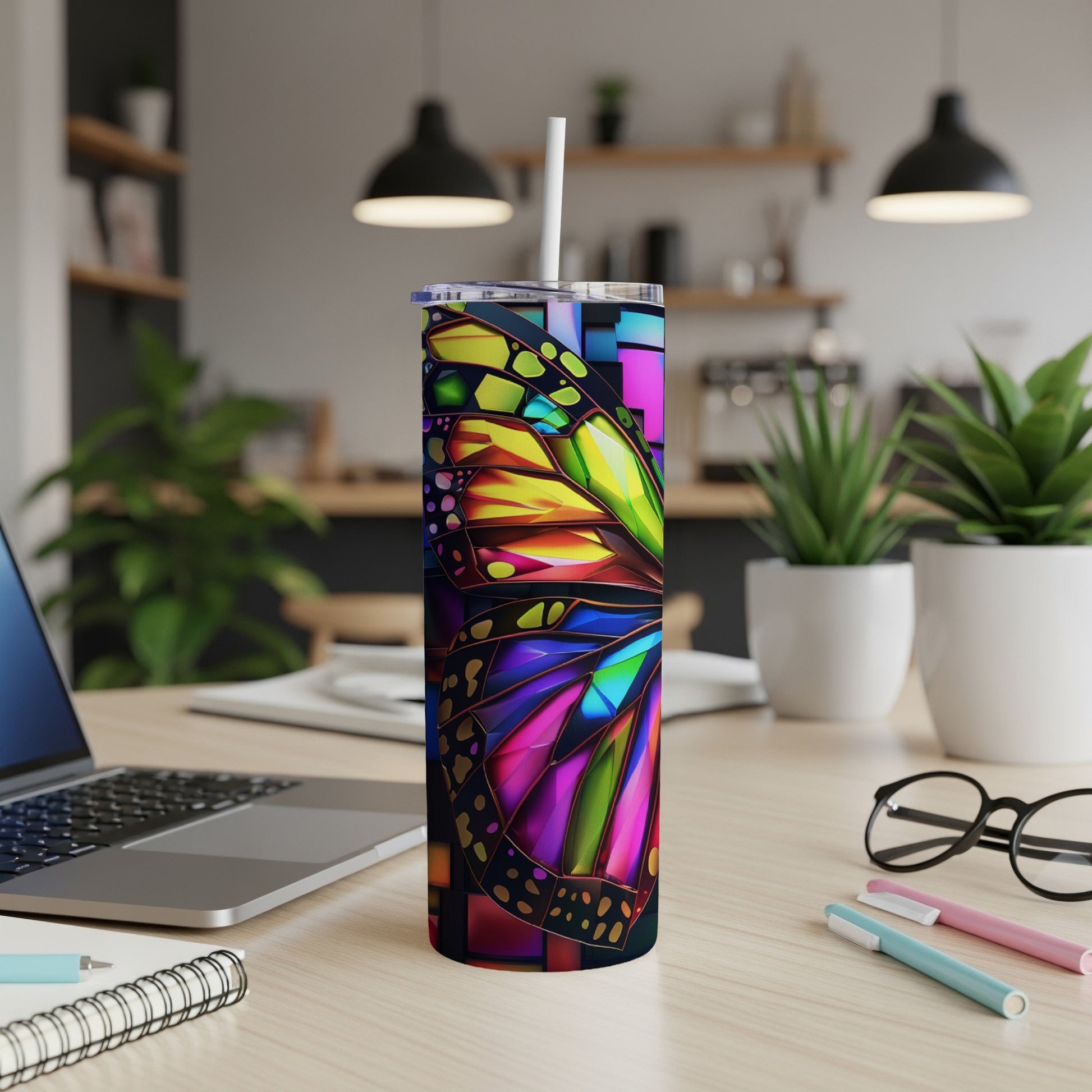 Butterfly pattern tumbler with straw on a desk.