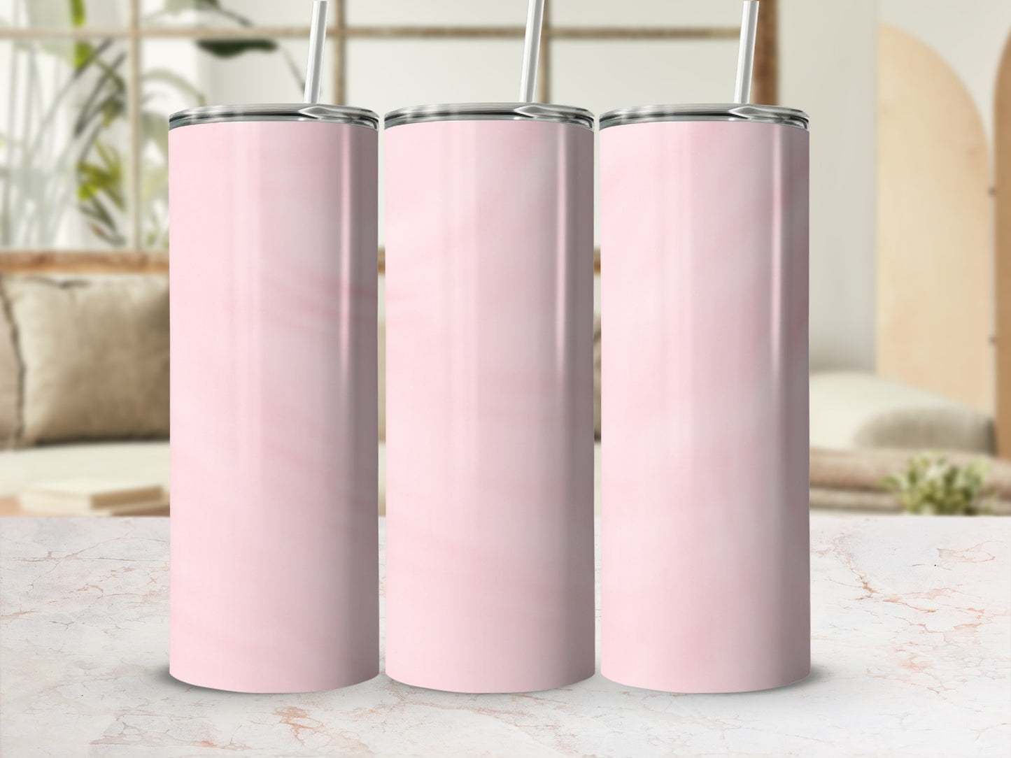 Three pink marble tumblers with straws stand on a marbled countertop.