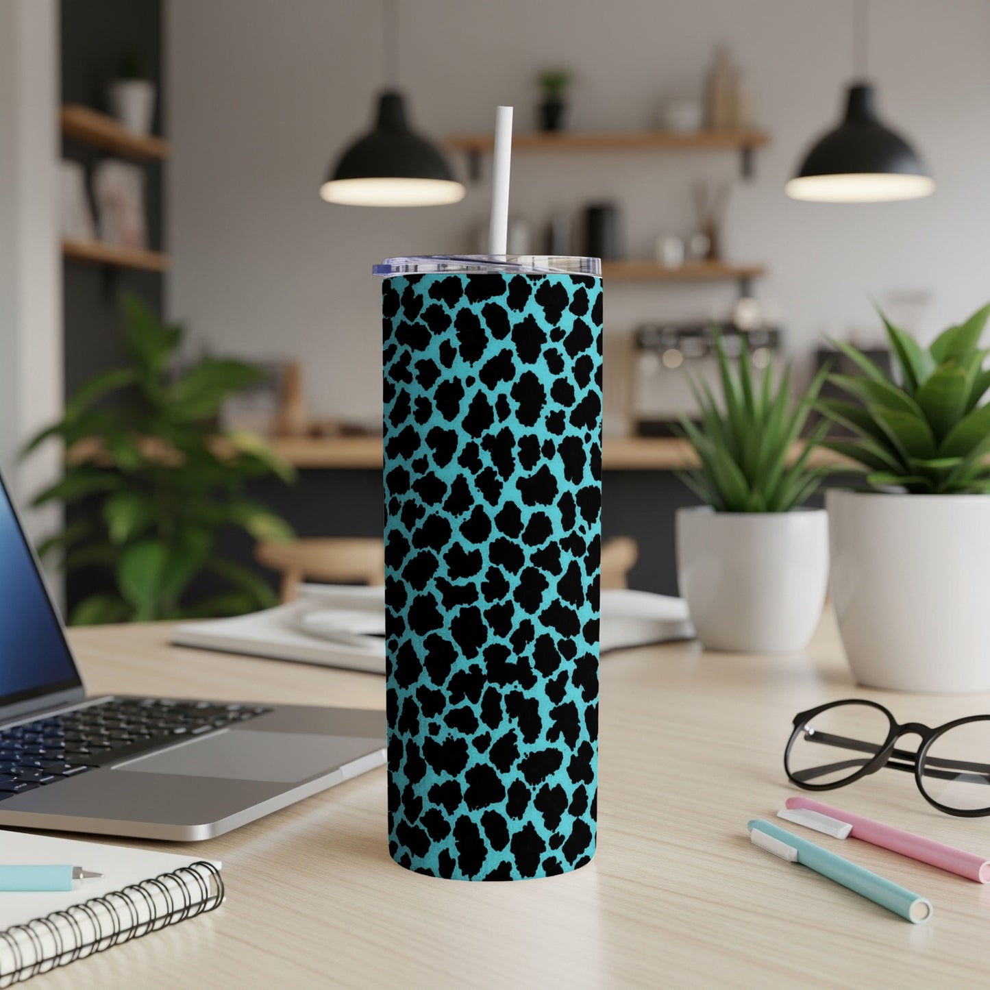 Blue leopard print tumbler with straw on a wooden desk.