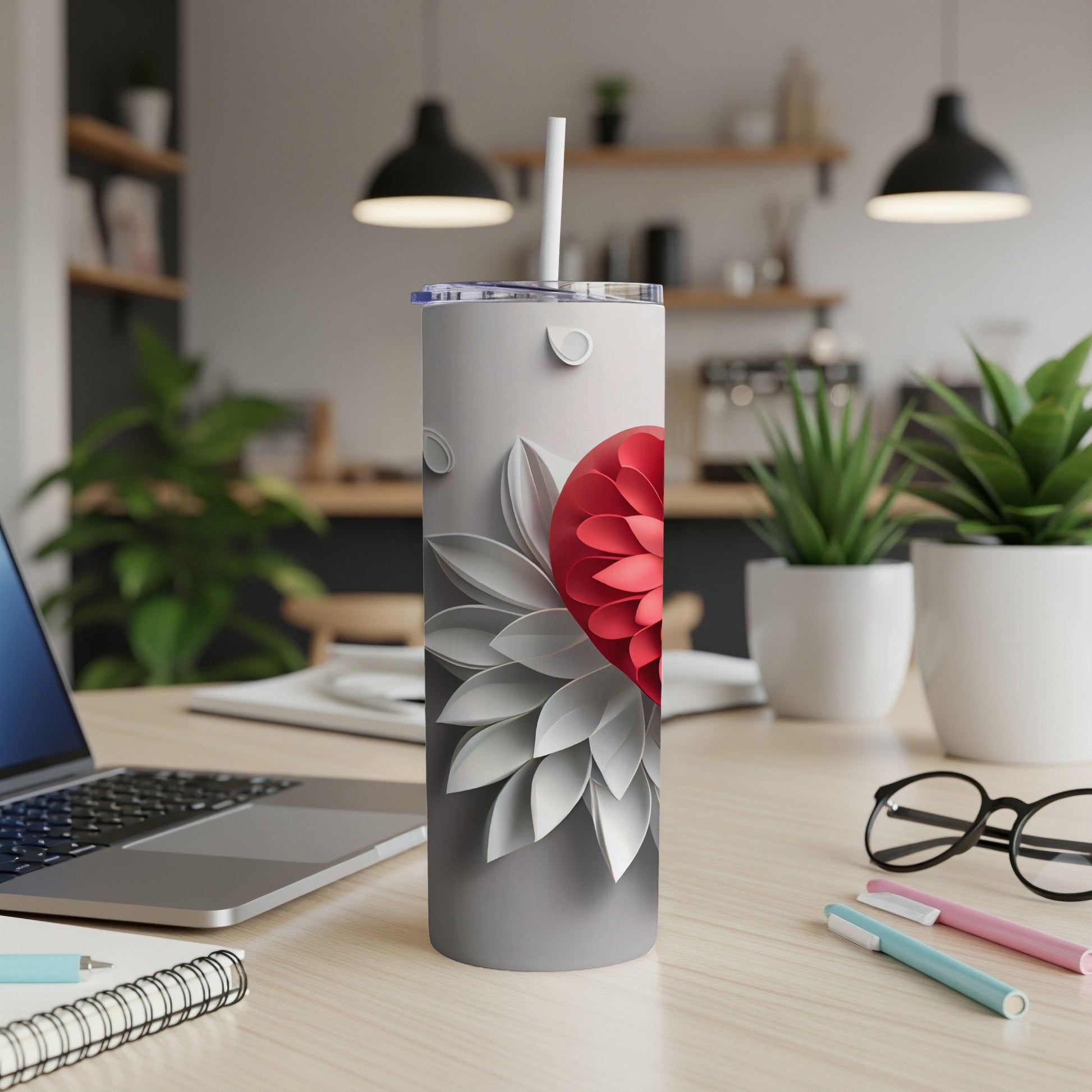 Gray tumbler with a red floral design and white petals.