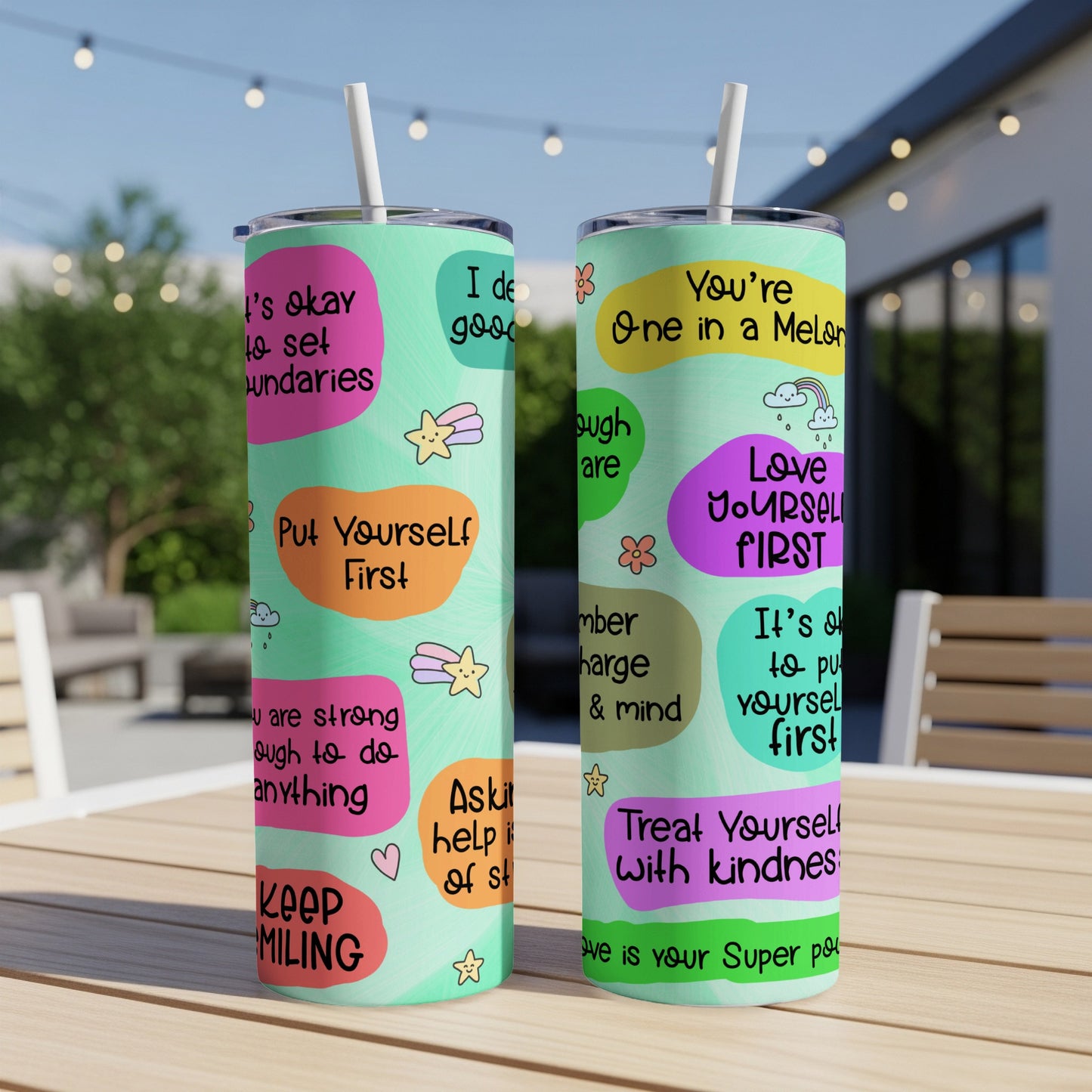 Two tumblers with motivational quotes and colorful illustrations on a table.