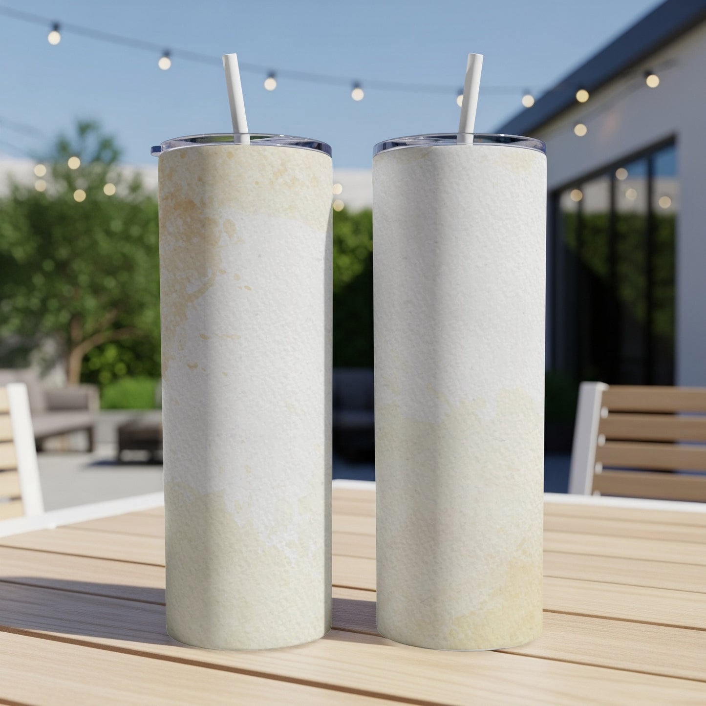Two tall, white tumblers with watercolor-like texture and straws on a wooden table.