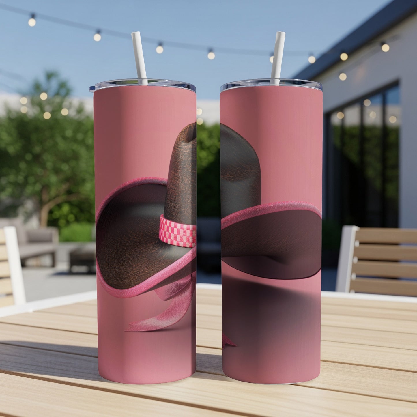Two pink tumblers with a sombrero design, resting on a wooden table.